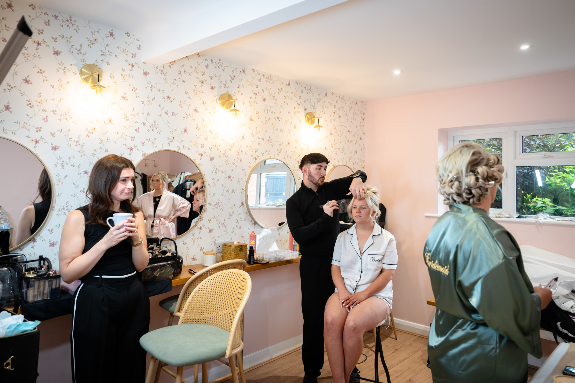 A wedding day at Hanbury Barns showing the bride having her hair styled in the dressing room, with a bridesmaid watching.