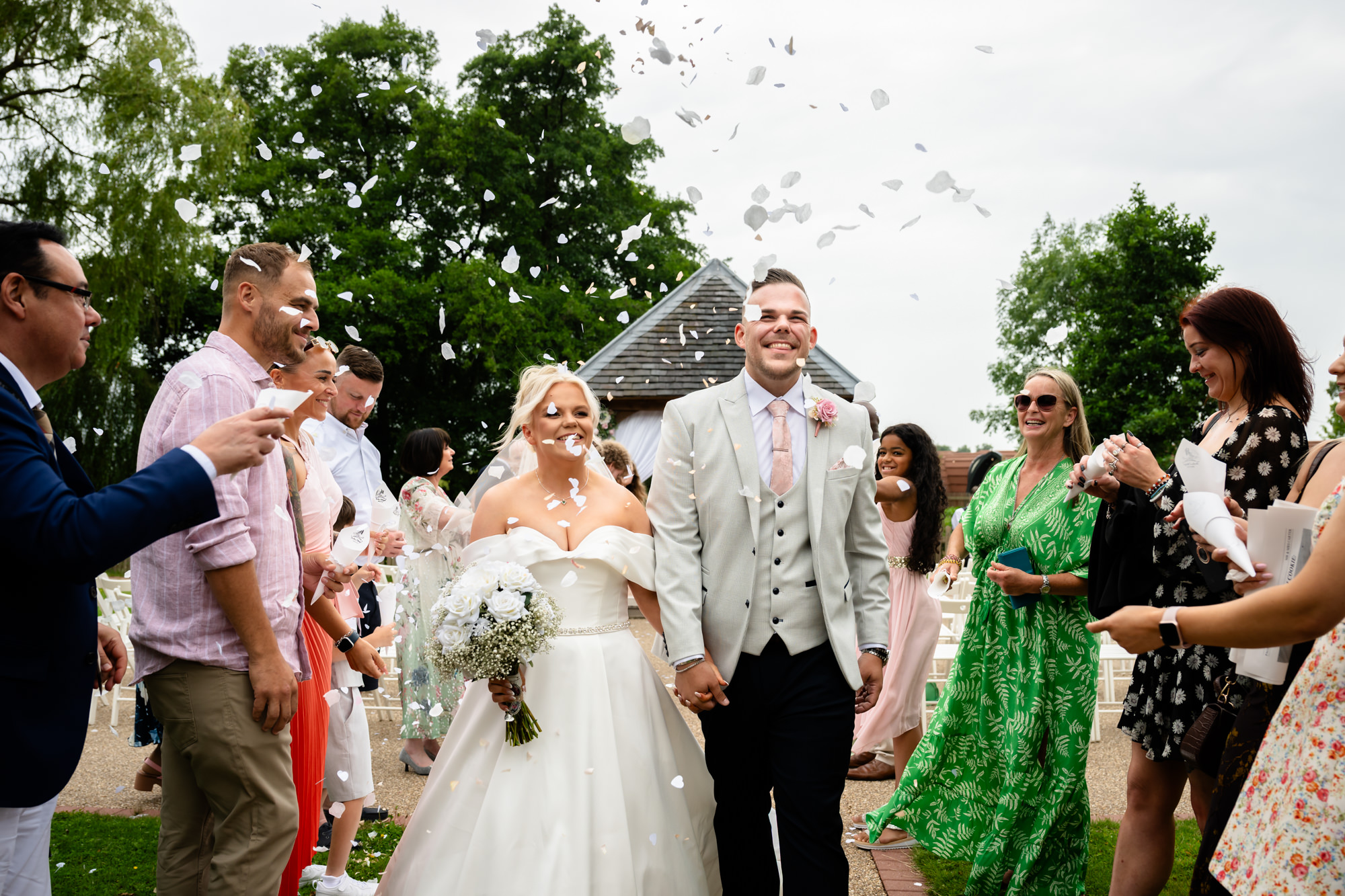 A wedding day at Hanbury Barns group shot of the beaming bride and groom exiting the ceremony surrounded by congratulating guests.