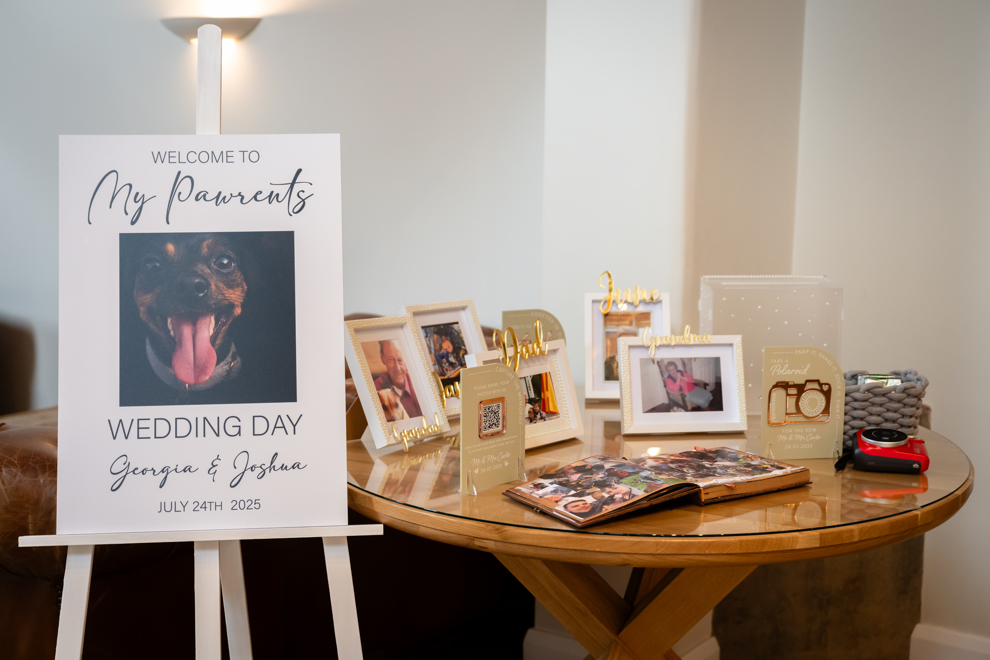 A beautifully set table at Hanbury Barns featuring a sign that reads Welcome to My Pawrents with a dog photo, and a collection of framed family photos.