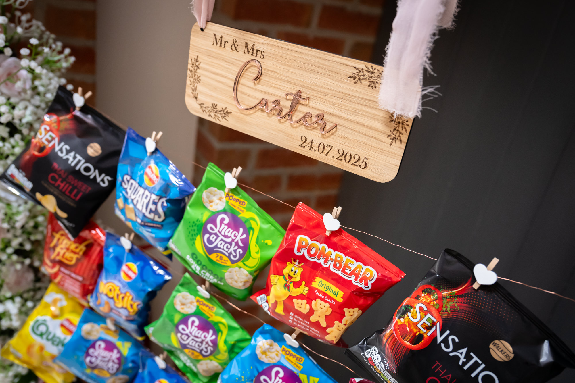 A fun wedding feature at Hanbury Barns, a crisp wall display, with a wooden Mr & Mrs sign hanging above popular crisp packets.