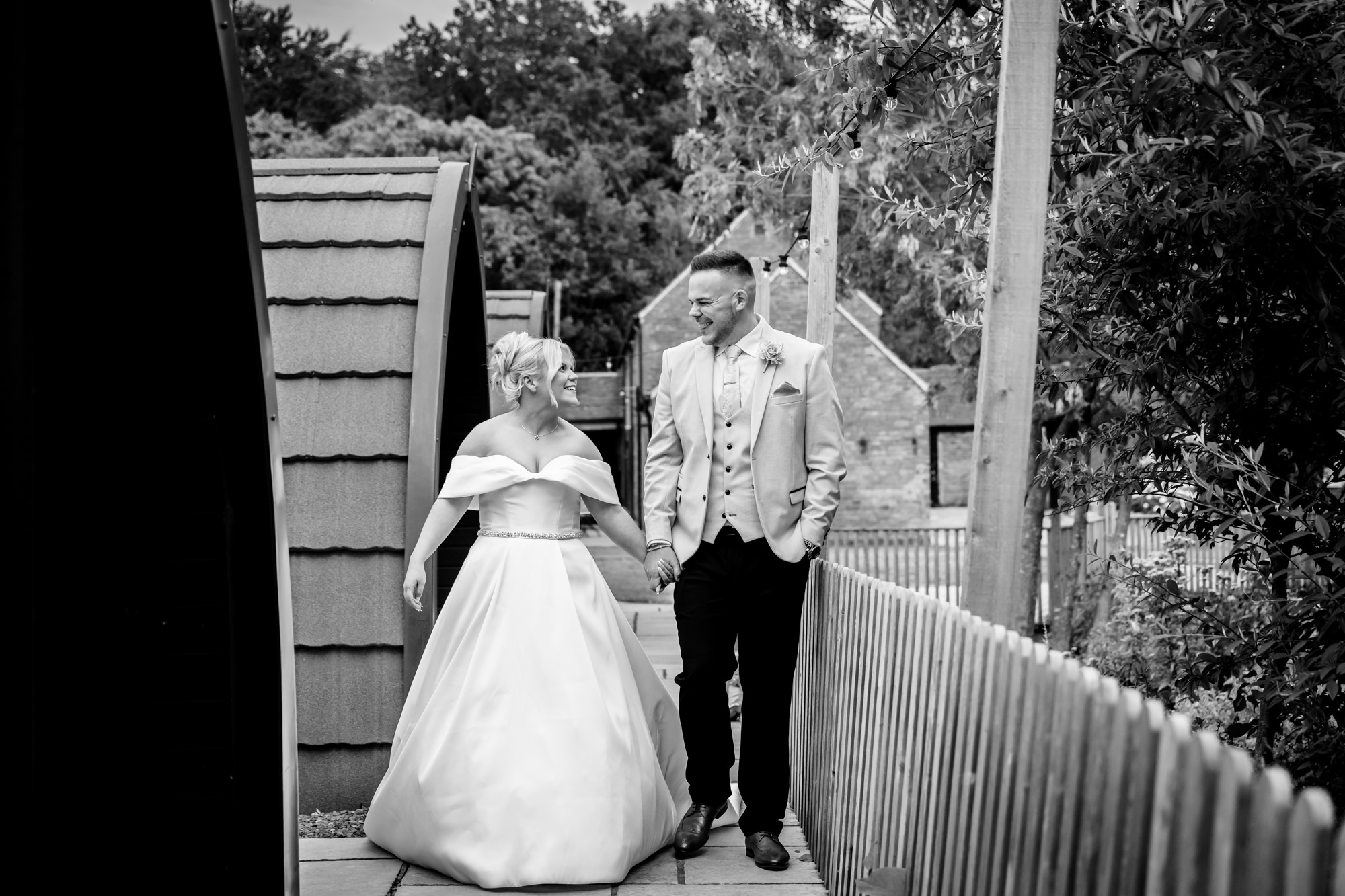 A couple's portrait at Hanbury Barns featuring the bride and groom walking hand-in-hand in a black and white shot