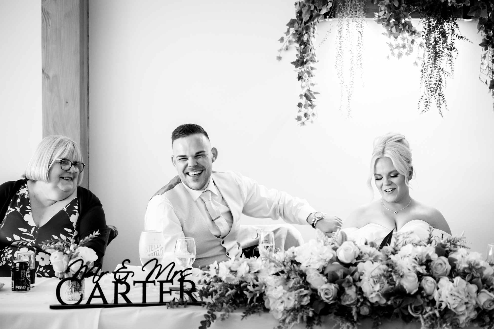 The married couple and a guest laughing heartily at a joke made during the wedding speeches at Hanbury Barns.