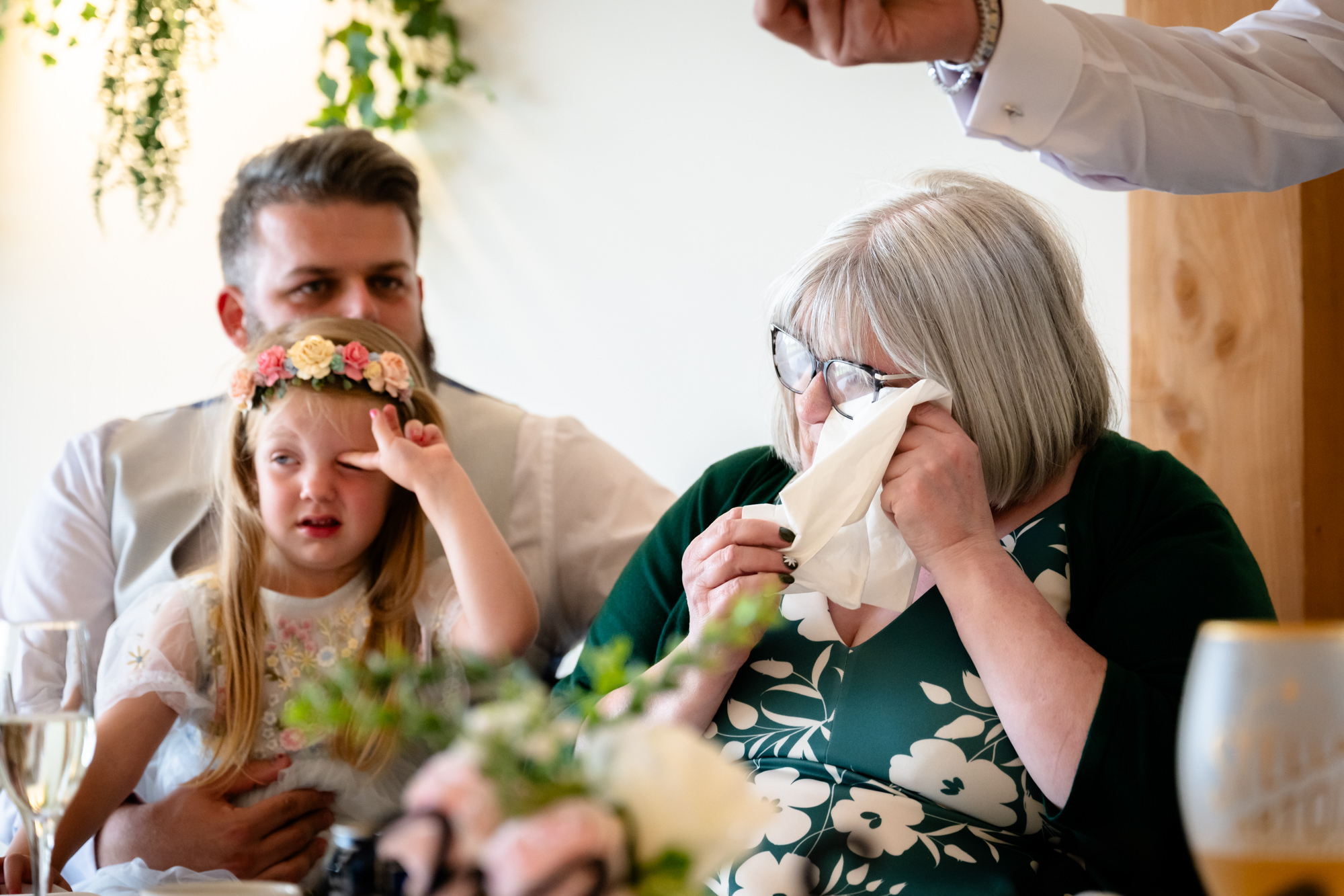 A touching reaction shot showing a guest wiping a tear away during one of the emotional wedding speeches at Hanbury Barns.