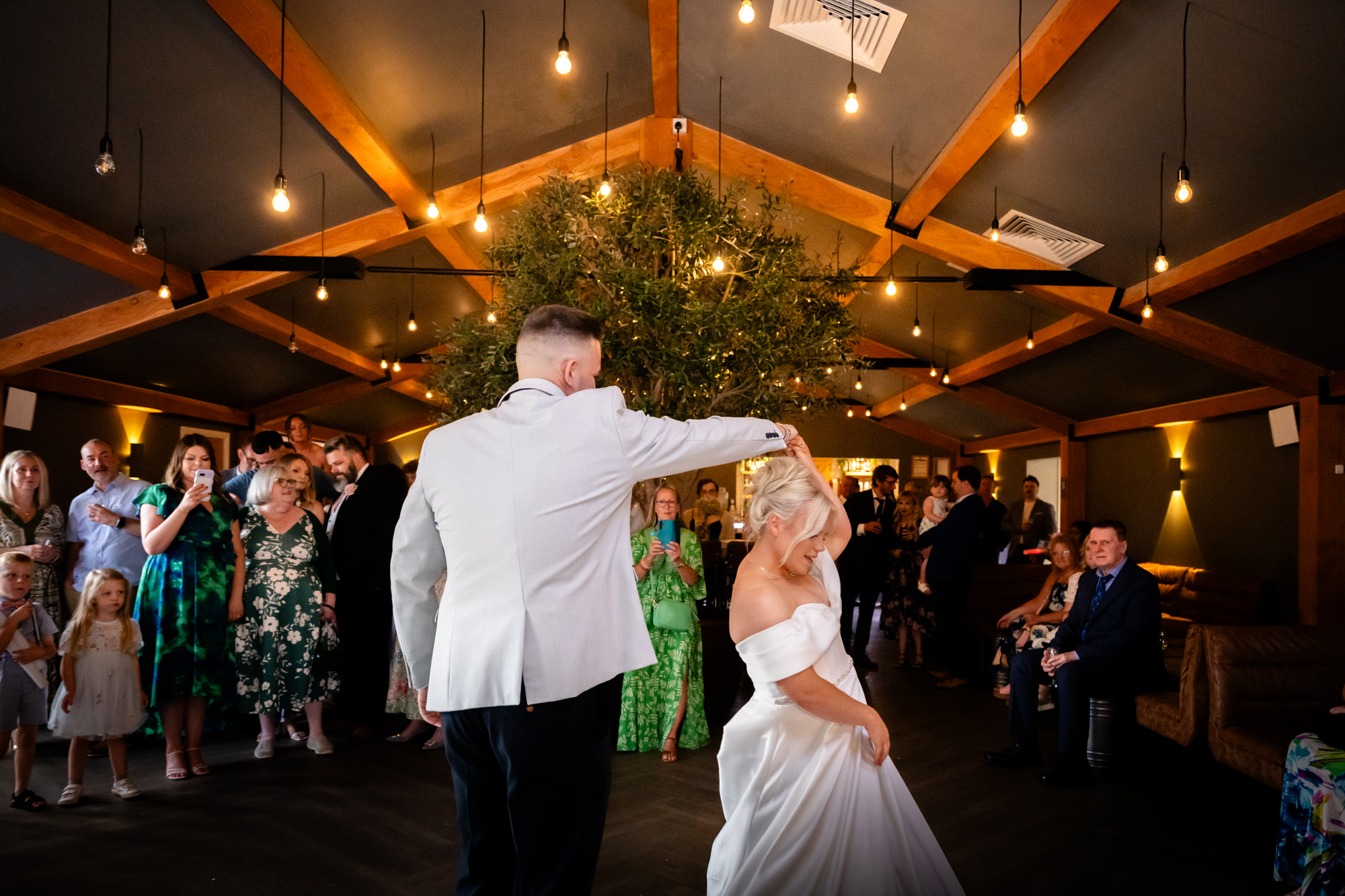 A stunning wedding at Hanbury Barns photo of the first dance, with the couple twirling on the dance floor surrounded by their guests.