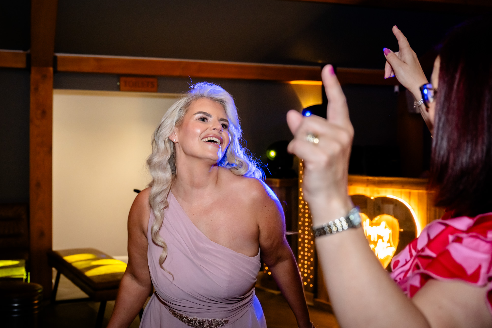 A great shot from the wedding at Hanbury Barns showing a group of guests cheering and raising their arms on the dance floor.