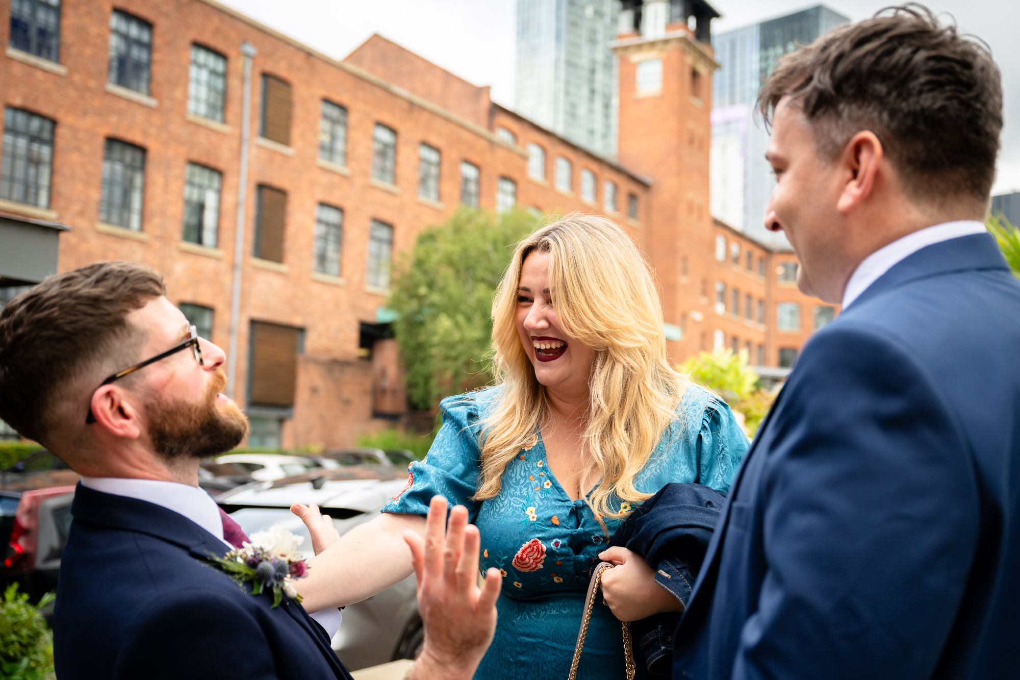 Wedding at Castlefield Rooms. Guests embrace outside, sharing a joyful hug, reflecting the warm atmosphere of the celebration.