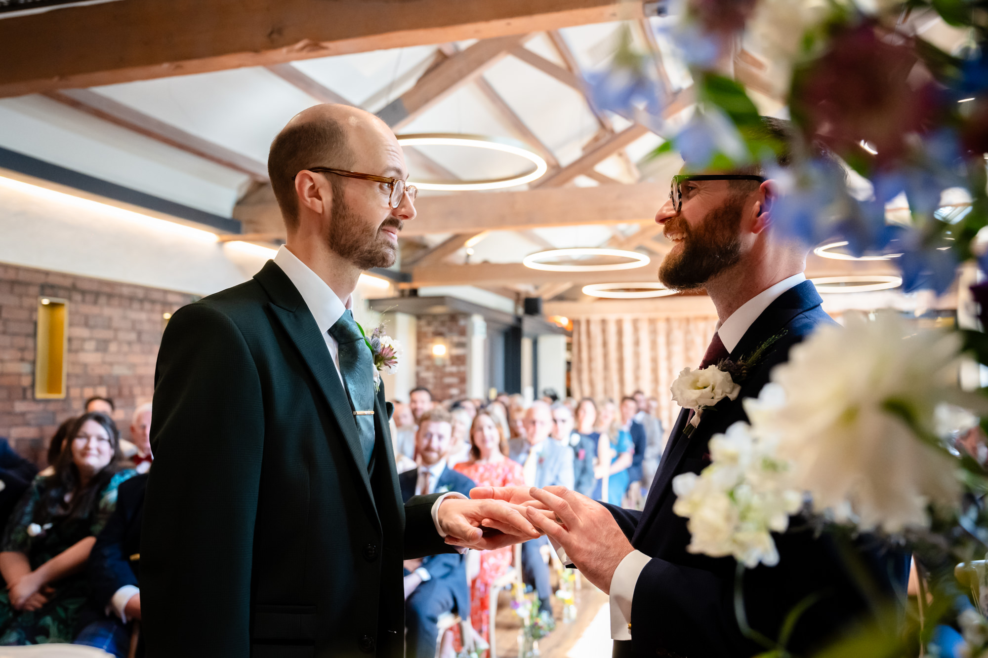 Wedding at Castlefield Rooms. The dark-haired groom picks up the ring from a friend.