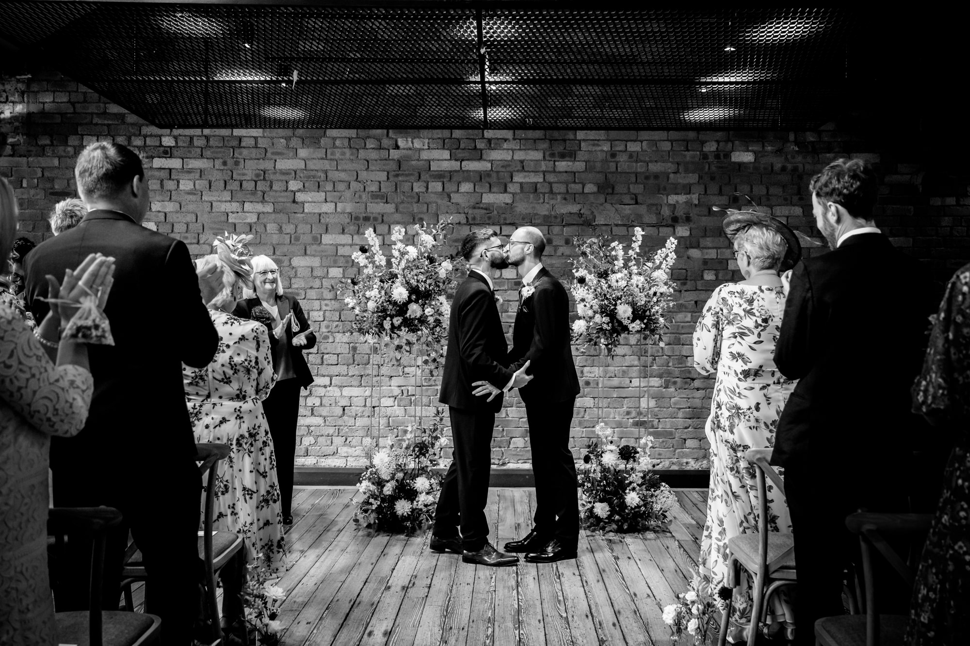 A moving black and white moment captured during the exchanging of rings between the two grooms at the Castlefield Rooms wedding ceremony.