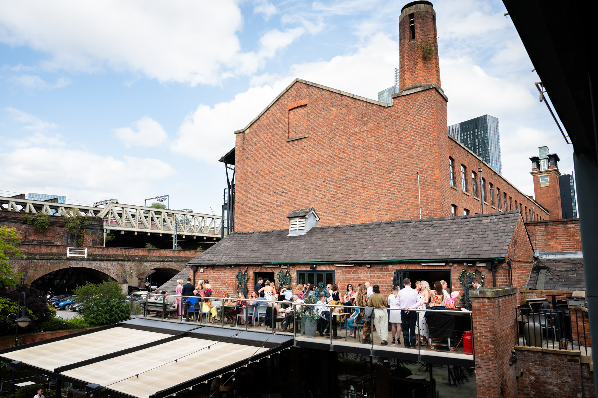 A guest hugging the drink who is holding a drink, celebrating the Castlefield Rooms wedding.
