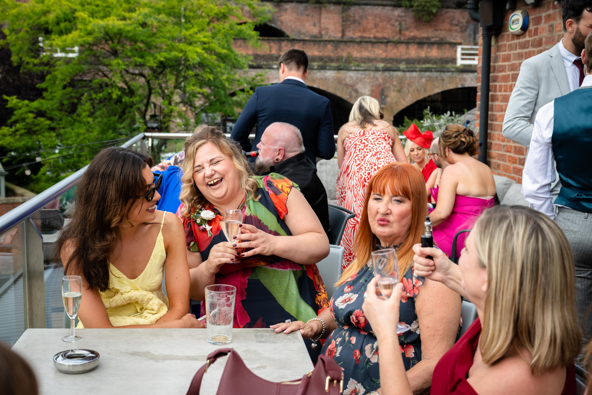 A panoramic view of the Castlefield Rooms outdoor terrace and guests mingling below the large brick chimney structure in the city.