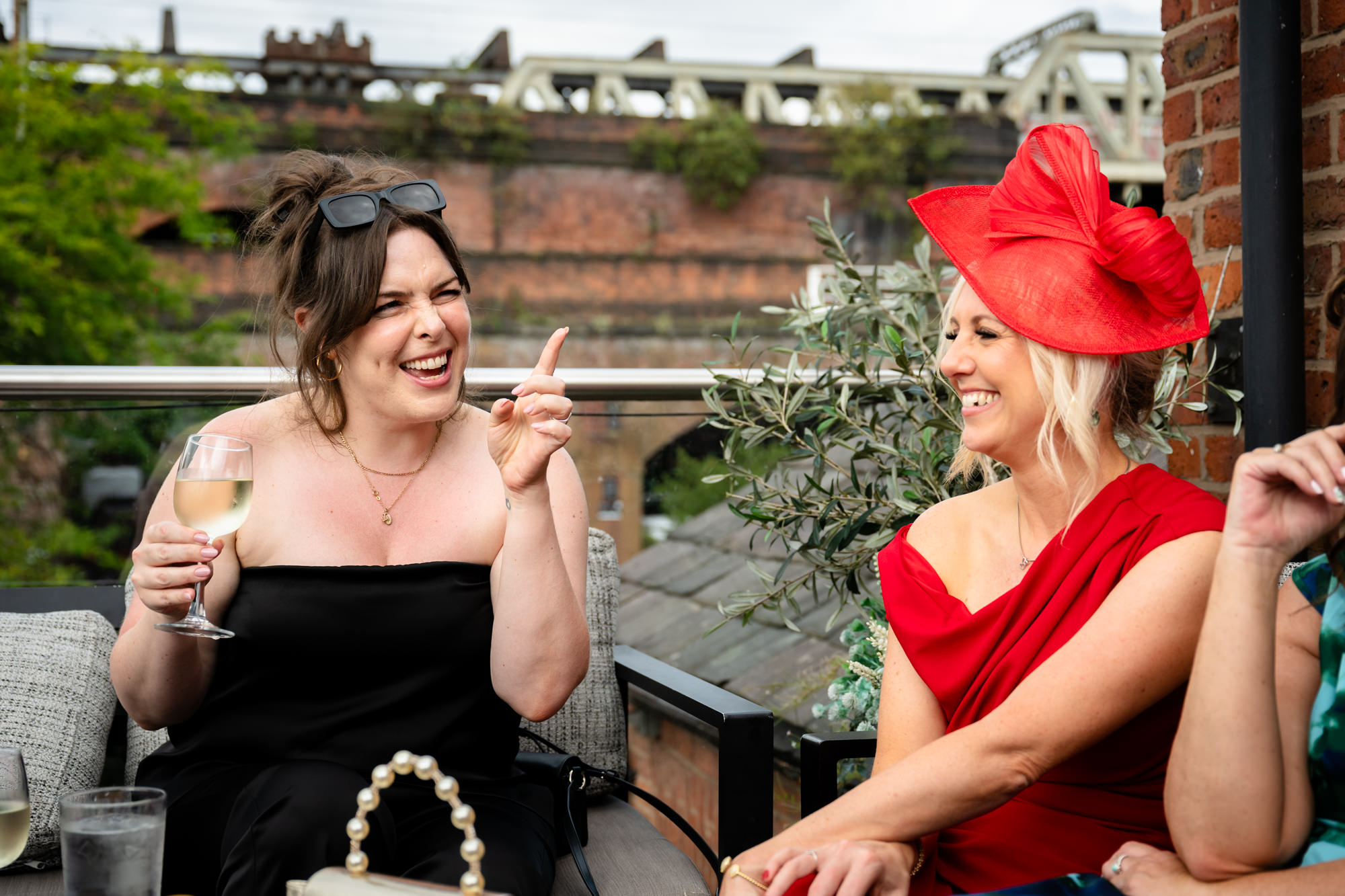 A close-up of three female guests laughing joyfully together during the drinks reception outside the Castlefield Rooms venue.