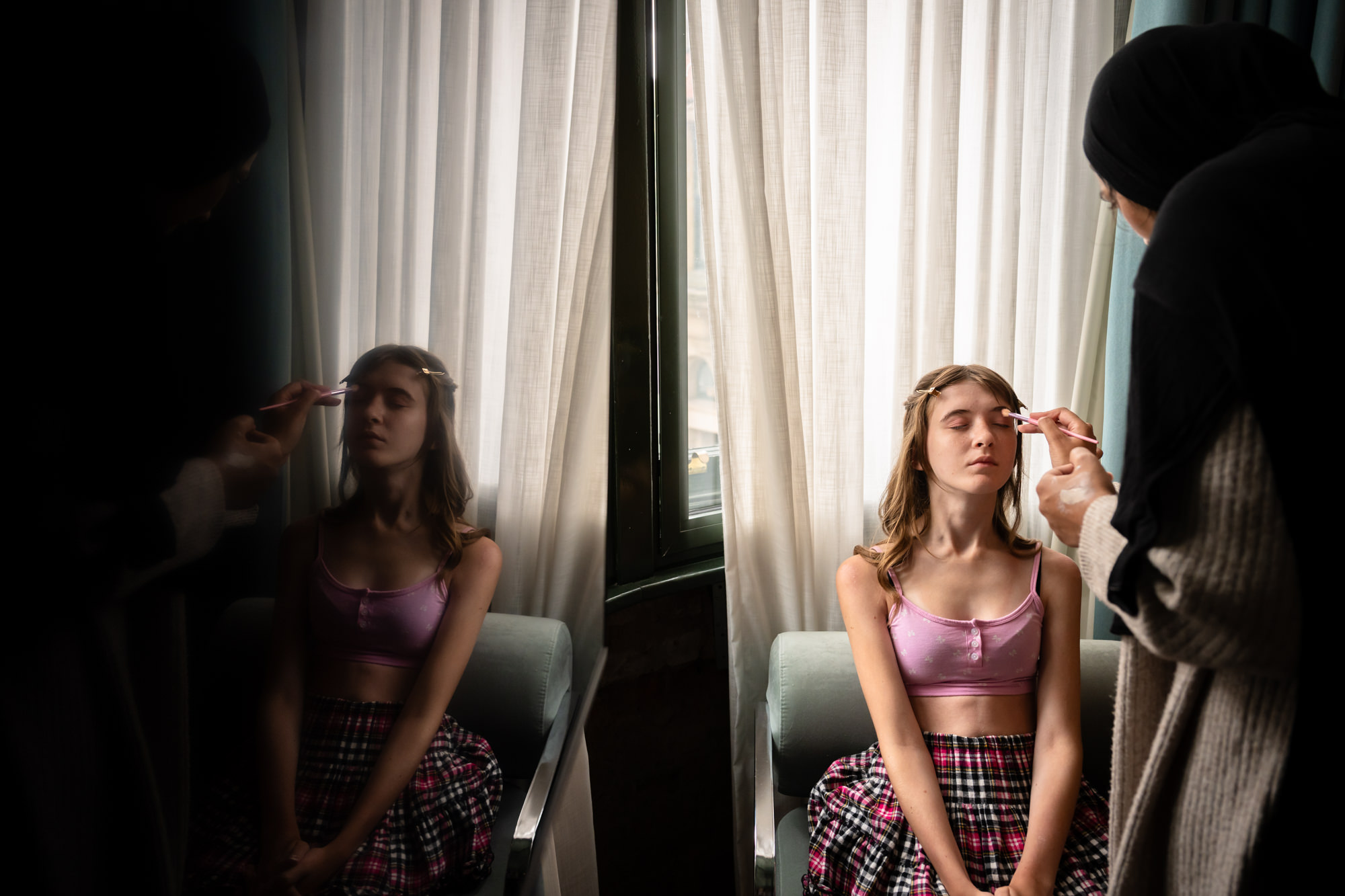 A guest in a leopard print top holds two white rose buttonholes during wedding preparations at The Alan hotel.