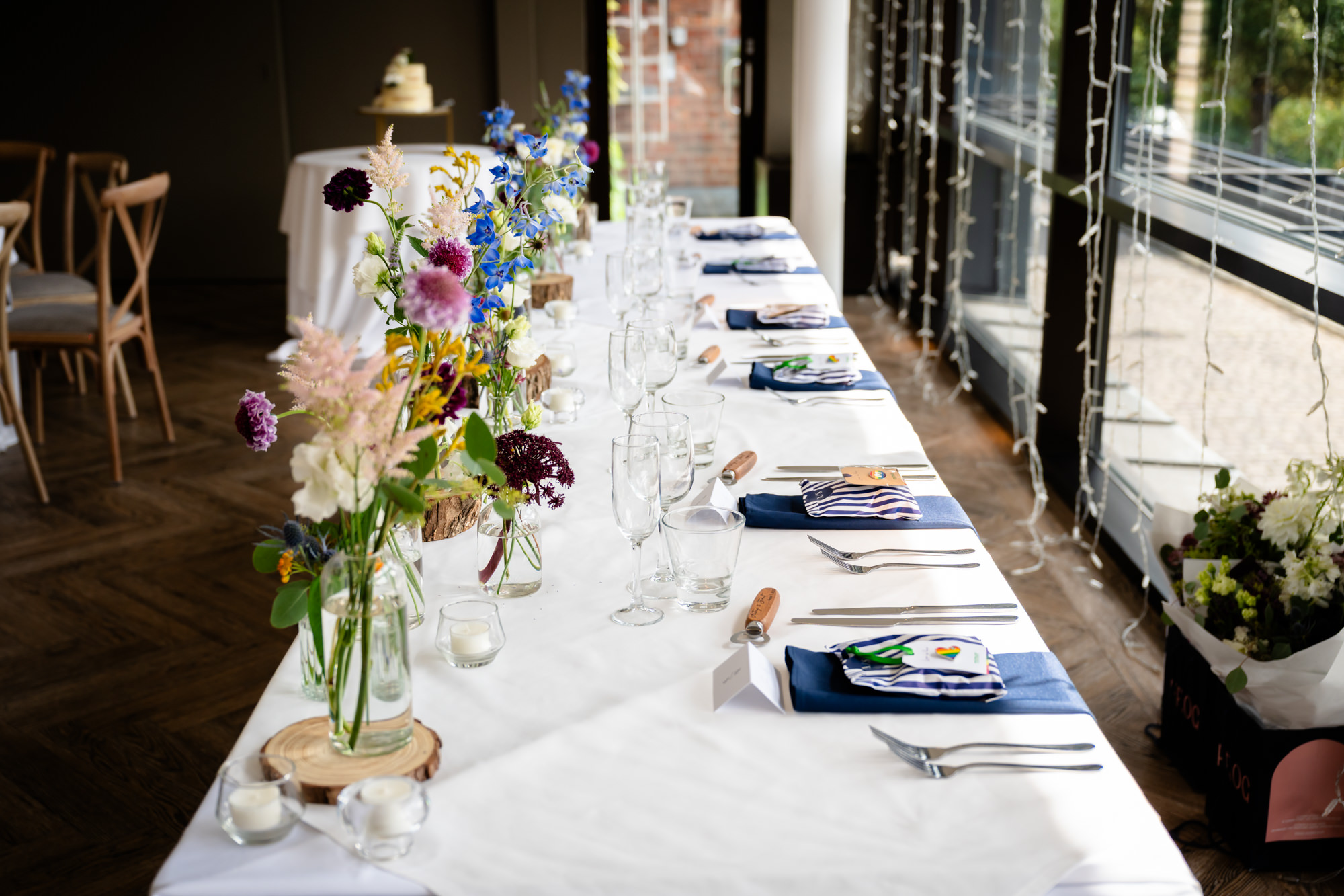 A beautifully decorated long table awaits the guests for the wedding breakfast, adorned with simple flower arrangements at Castlefield Rooms.