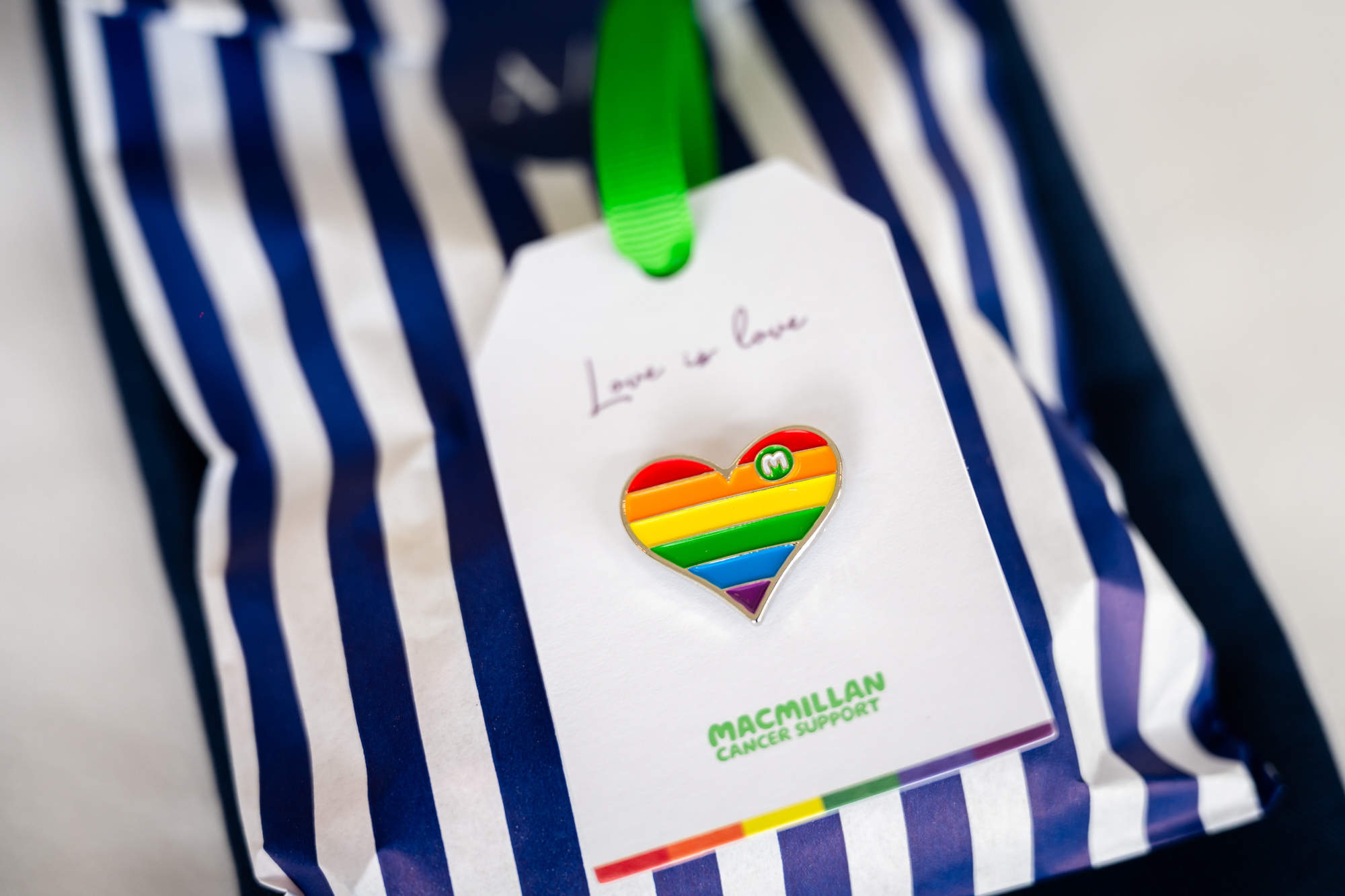 Wedding at Castlefield Rooms. A close-up of wedding favors wrapped in a blue and white striped bag, with a tag featuring a rainbow heart to celebrate the couple.