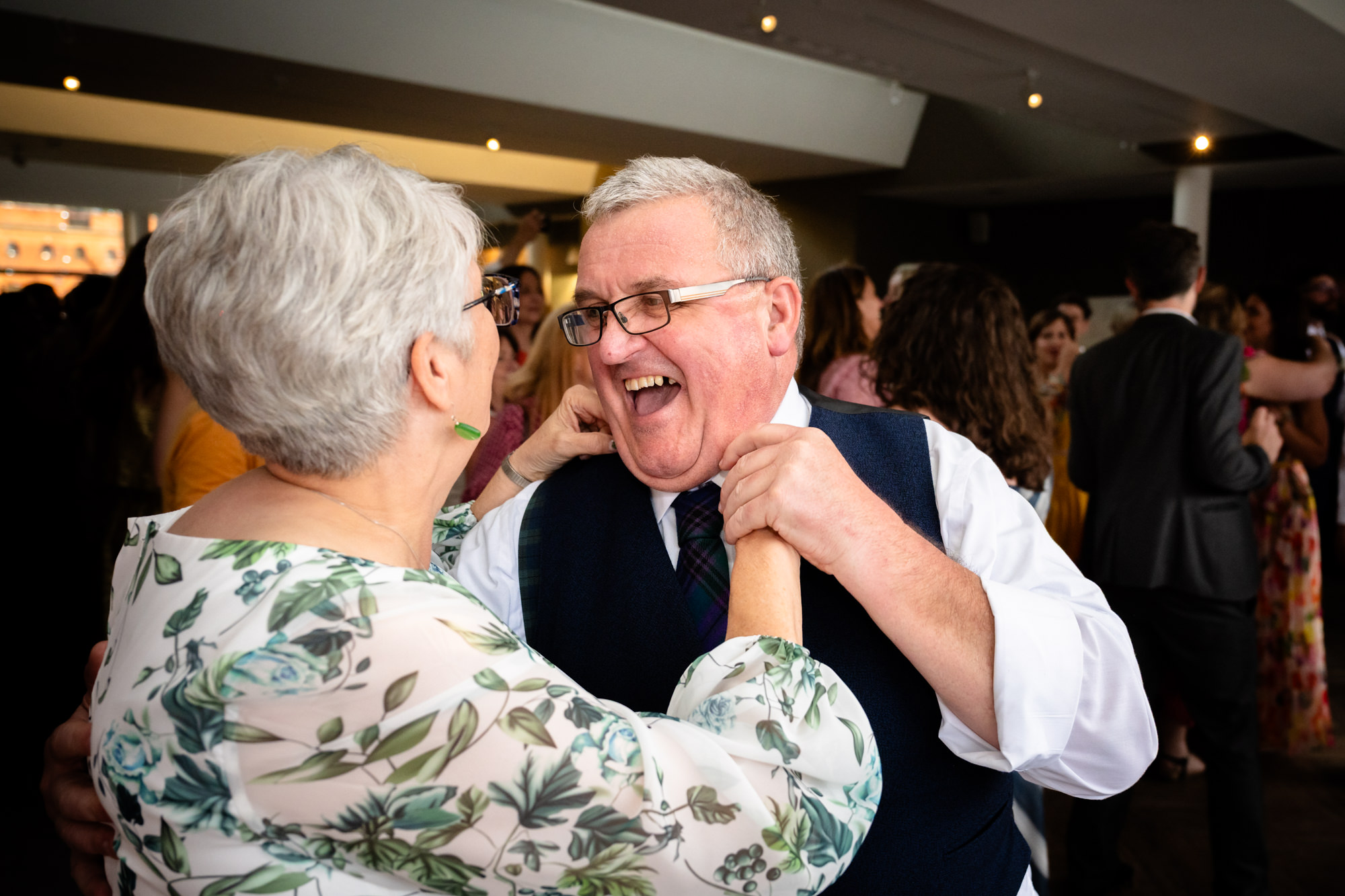 Wedding at Castlefield Rooms. The two grooms extend their arms and spin around on the dance floor during their lively and energetic first dance.