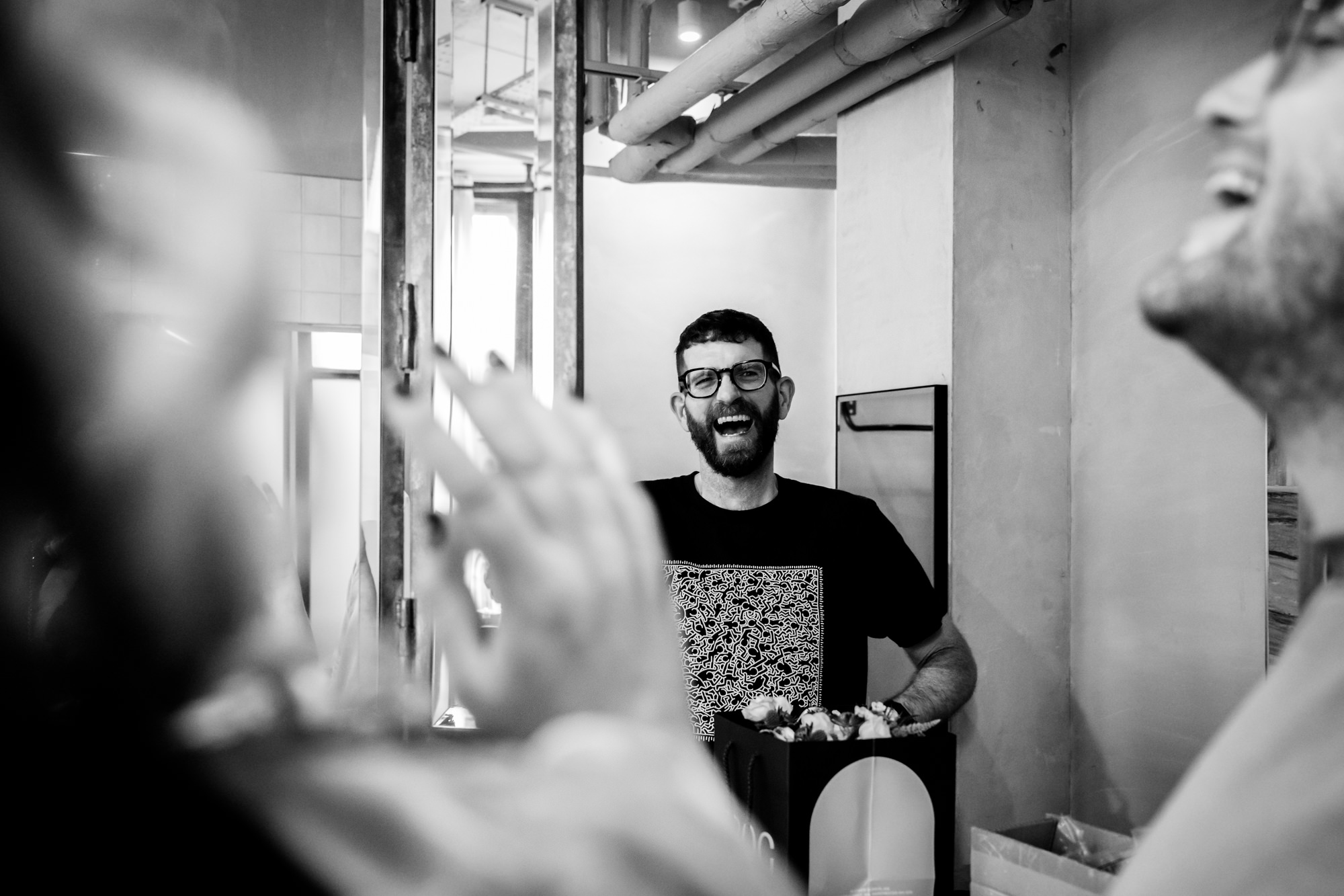 A guest in a leopard print top reacts with a surprised expression while looking into a handheld mirror during wedding preparations at The Alan hotel.