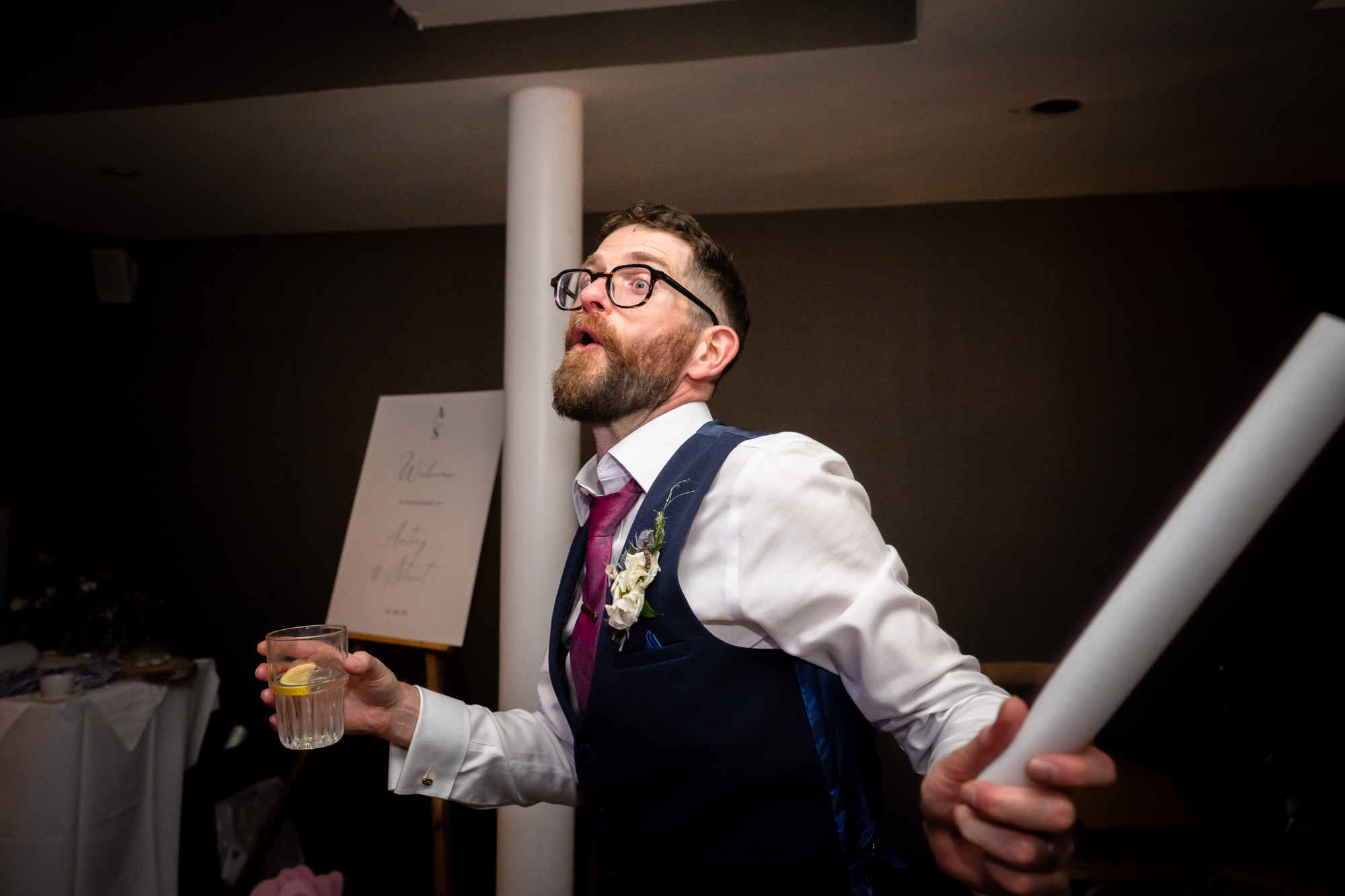 The groom in the green suit high-fives a guest on the crowded dance floor, enjoying the party and dancing under the high ceiling at Castlefield Rooms.