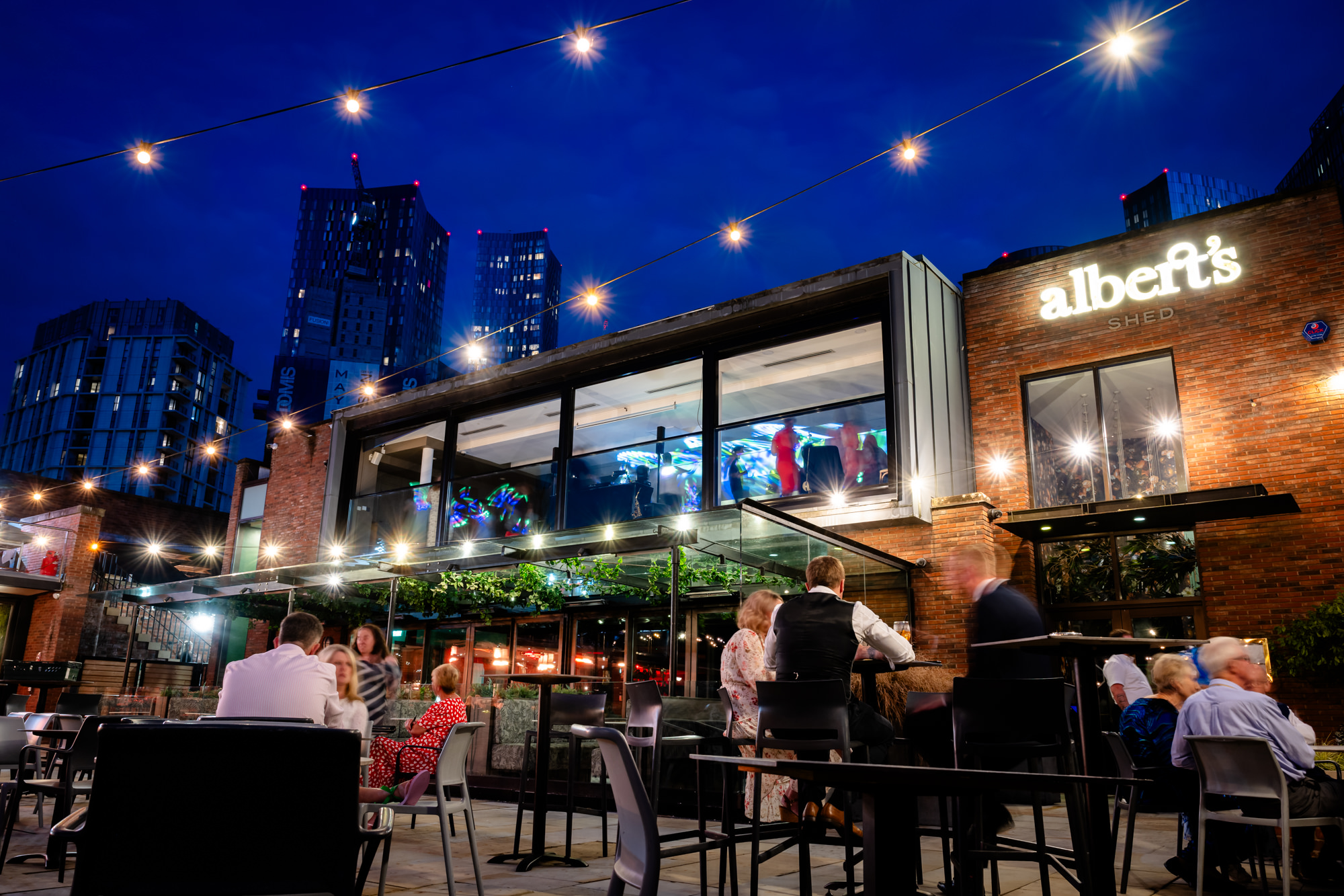 A beautiful night-time exterior view of the Castlefield Rooms venue, with string lights illuminating the outdoor terrace where guests are visible. Export to Sheets A beautiful night-time exterior view of the Castlefield Rooms venue, with string lights illuminating the outdoor terrace where guests are visible. Export to Sheets