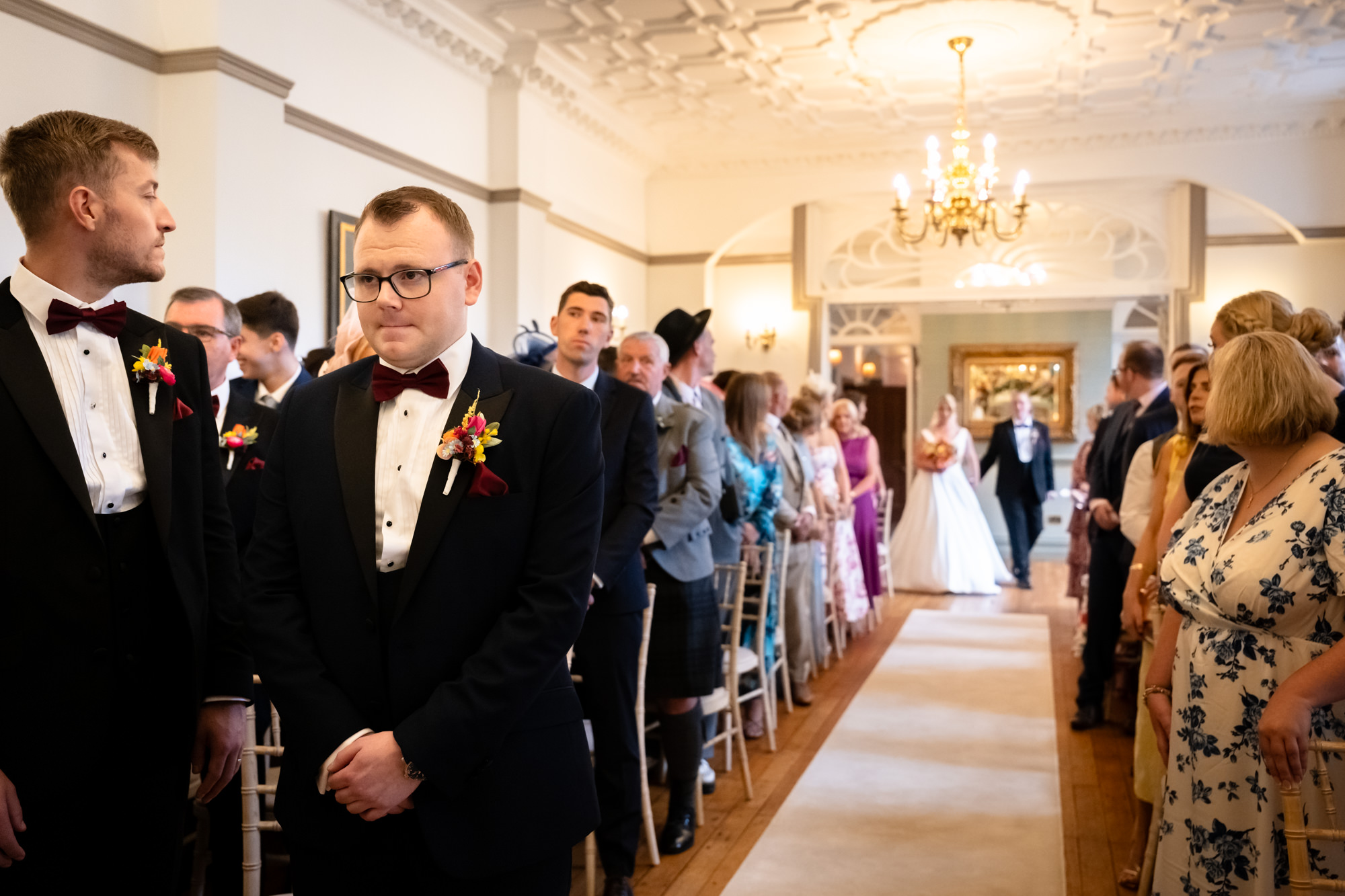 The groom watching with emotion as the bride begins her walk down the aisle during a wedding at Nunsmere Hall.