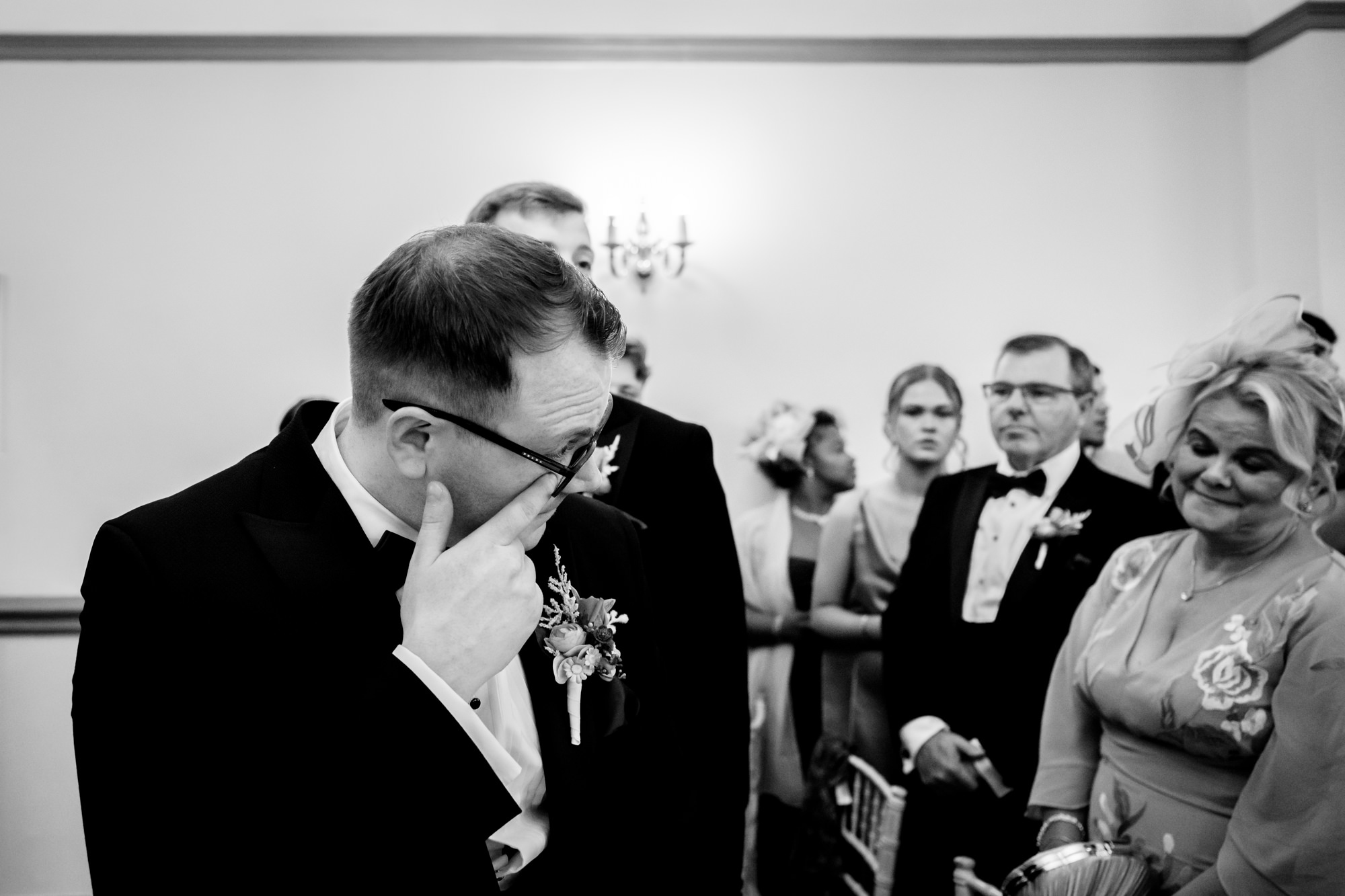 The groom wiping a tear from his eye as he stands at the altar at Nunsmere Hall.