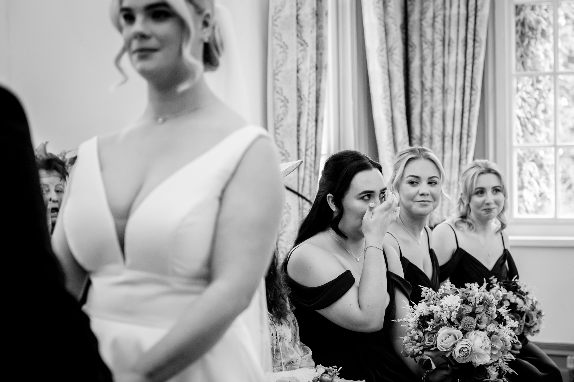 Bridesmaids wiping away tears during the emotional wedding vows at Nunsmere Hall.