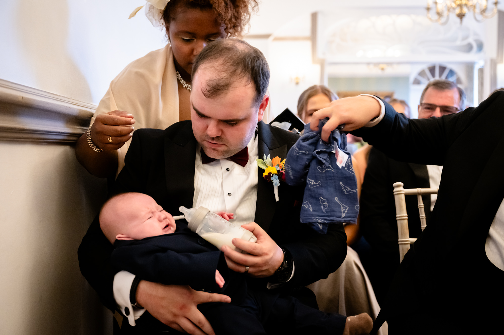 A guest trying to feed a crying baby during the wedding ceremony at Nunsmere Hall.