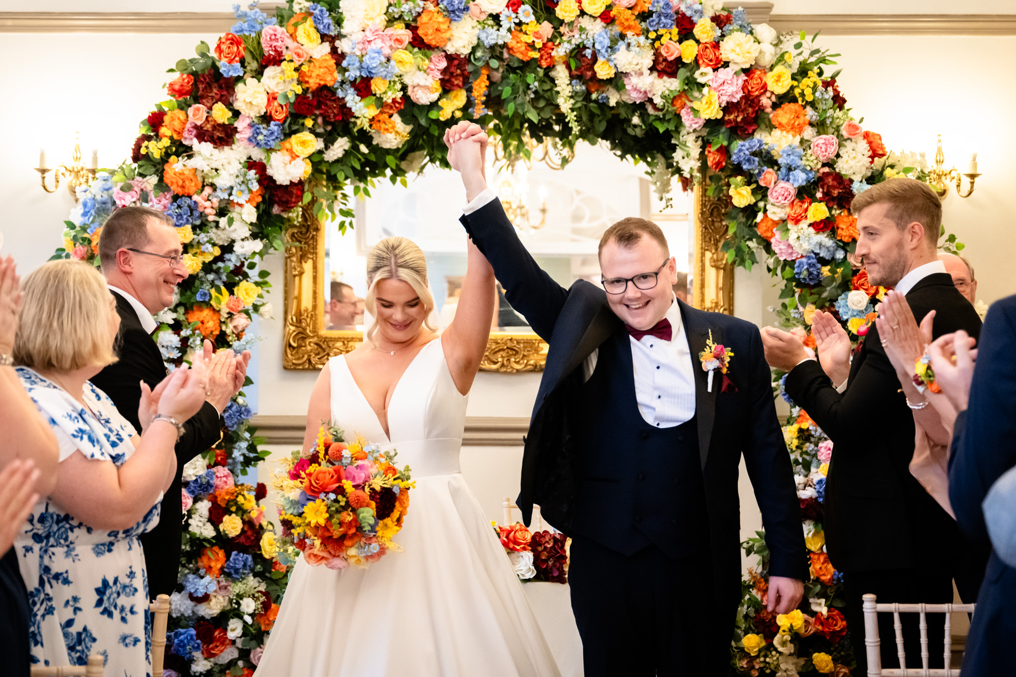 The bride and groom celebrating with hands in the air after being pronounced husband and wife during their wedding at Nunsmere Hall.