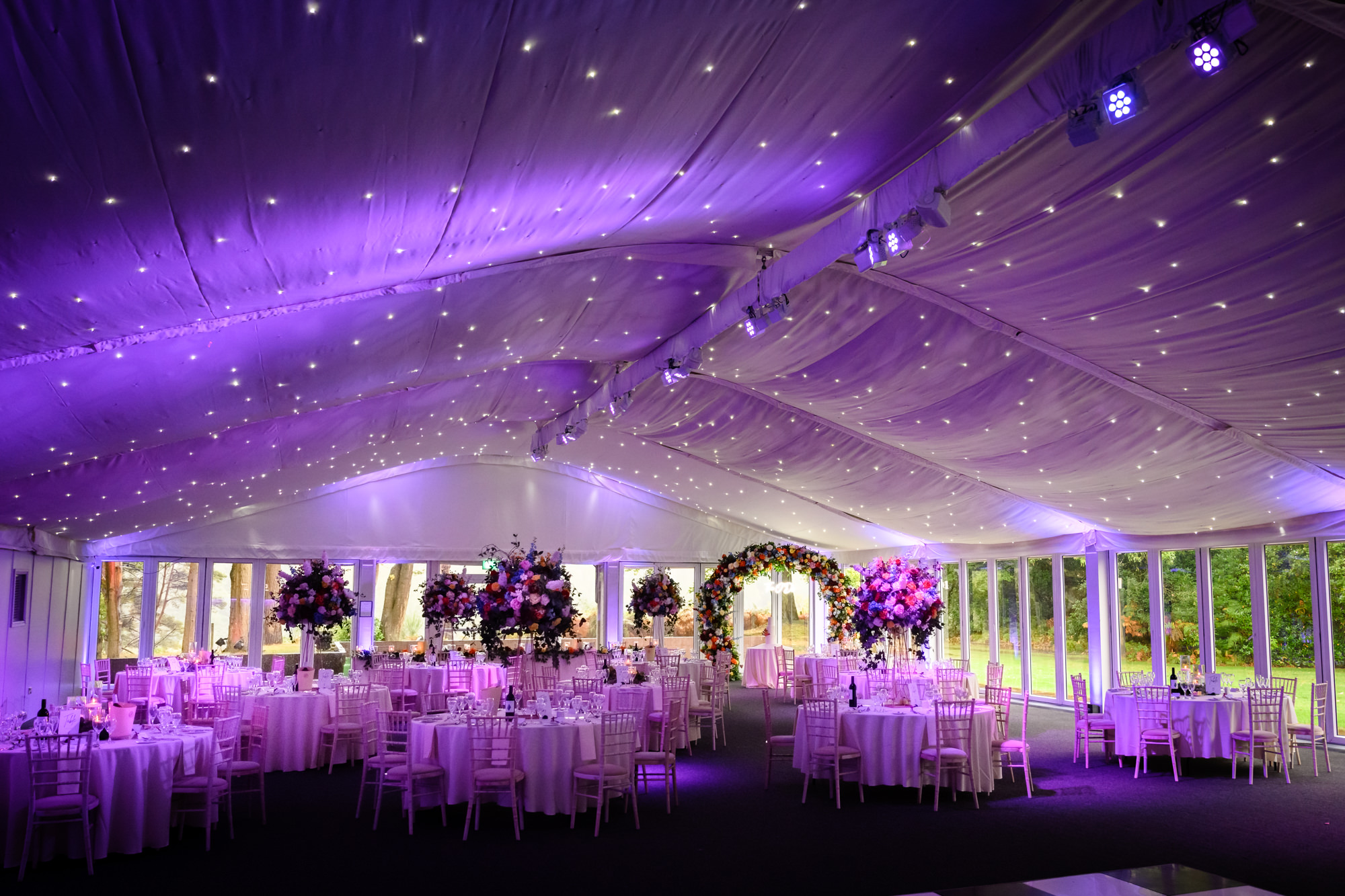 Wide shot of the marquee reception room for a wedding at Nunsmere Hall featuring purple lighting and a star cloth ceiling.
