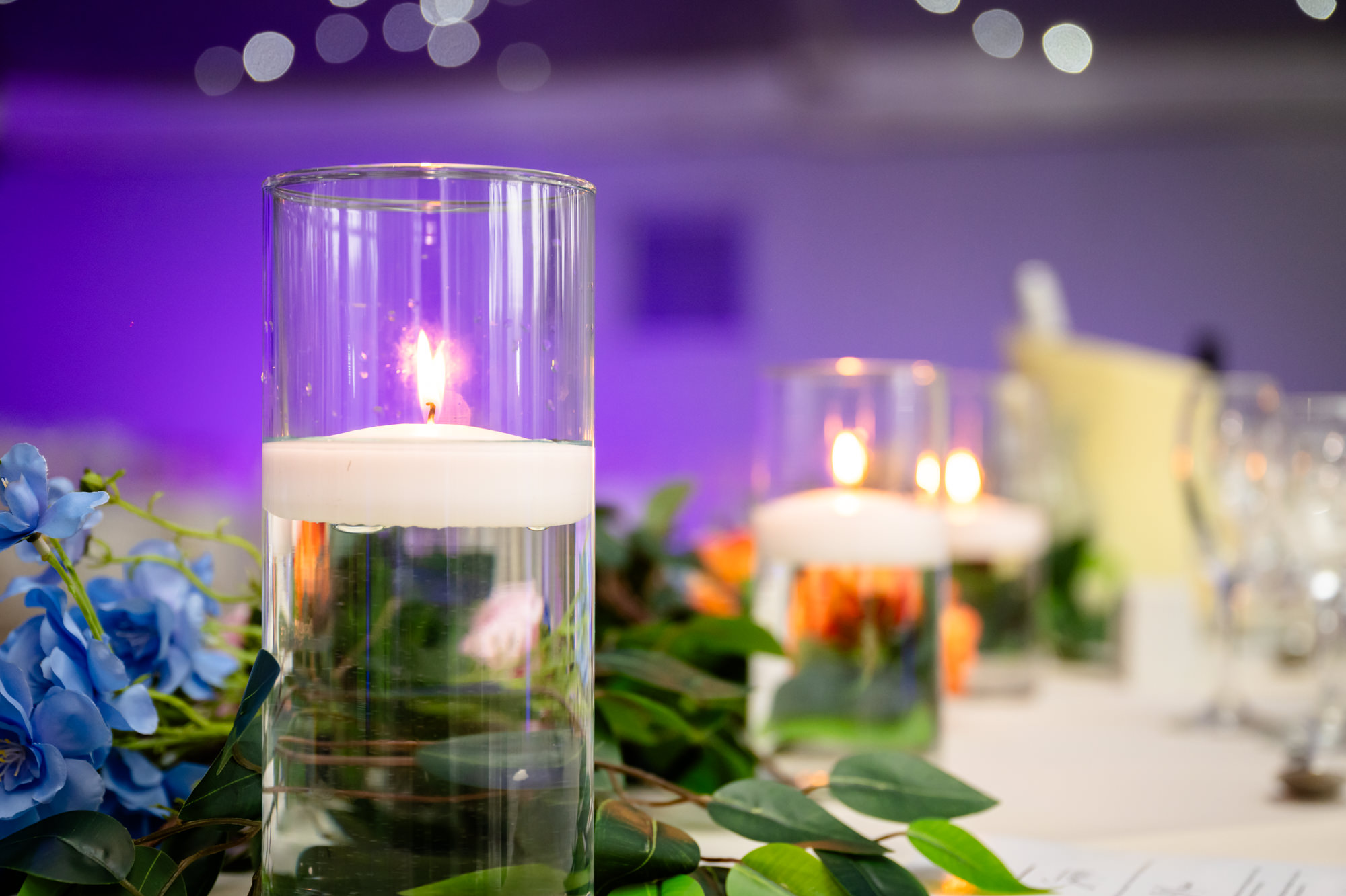 Close up detail of a glass candle holder and floral centerpiece in the marquee at Nunsmere Hall.