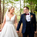 The bride and groom walking hand in hand through the woods during their wedding at Nunsmere Hall.