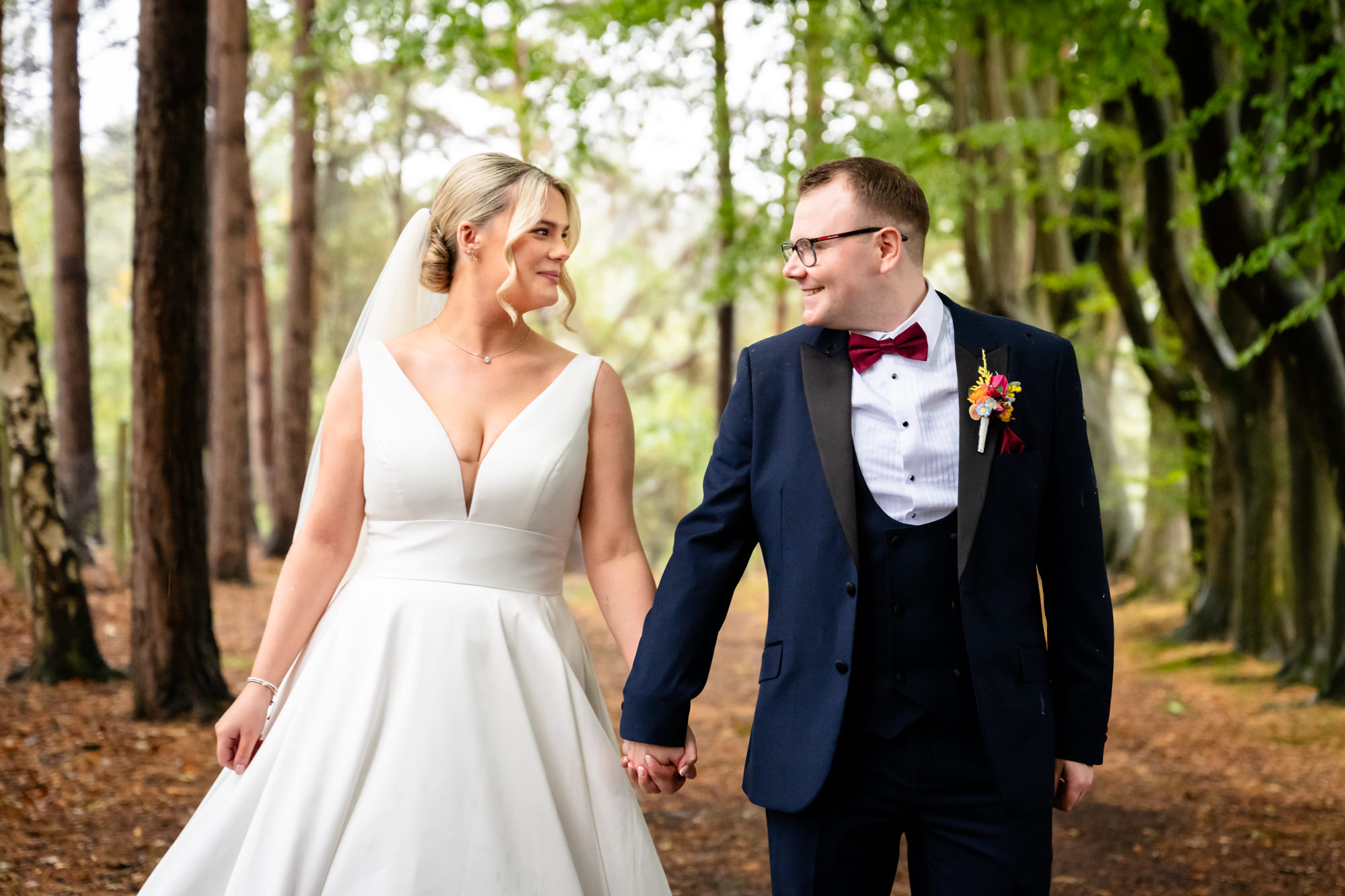 The bride and groom walking hand in hand through the woods during their wedding at Nunsmere Hall.