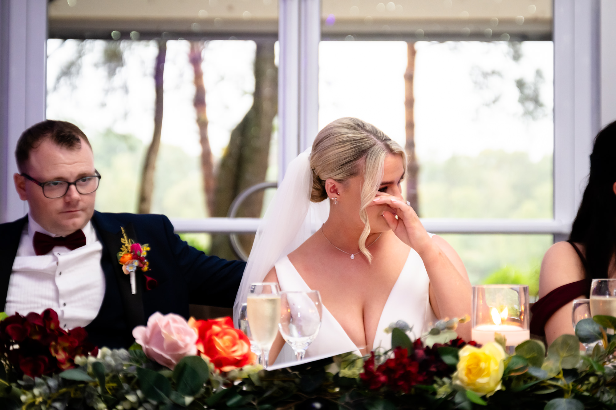 The bride wiping a tear during an emotional speech at a wedding at Nunsmere Hall.