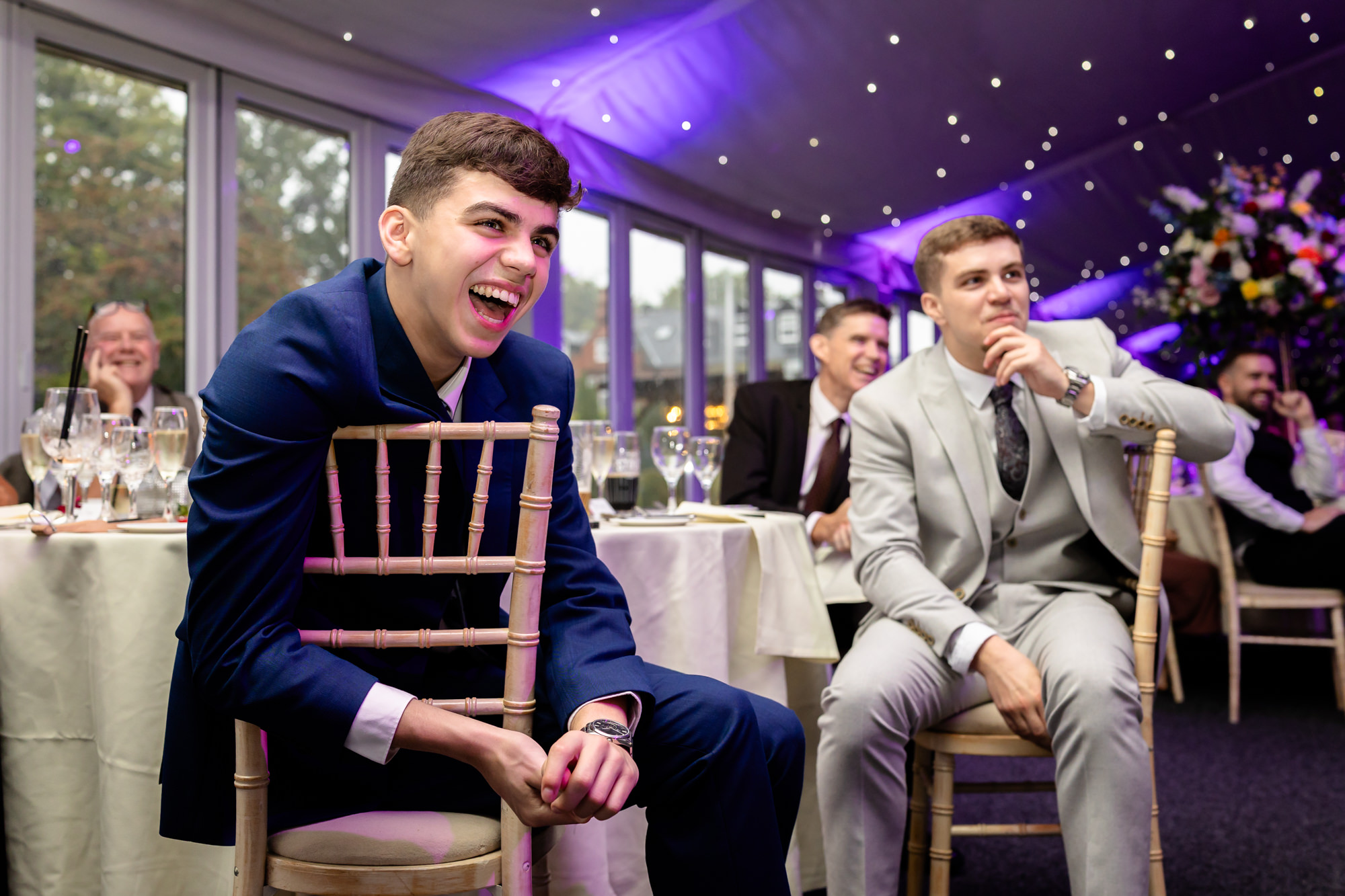 Guests seated at round tables at Nunsmere Hall laughing at a joke during the speeches.