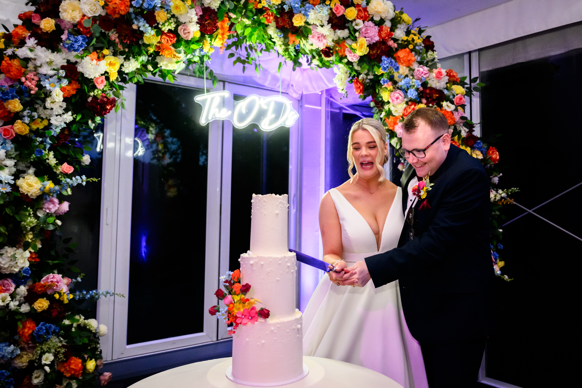 The bride and groom cutting their white three tier cake during a wedding at Nunsmere Hall.