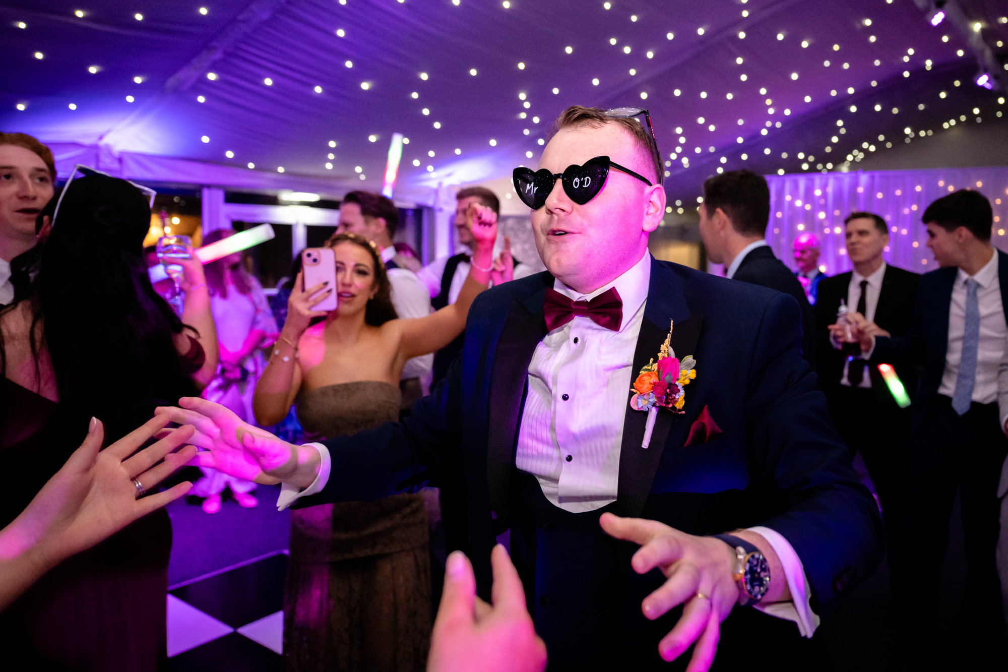The groom wearing heart shaped sunglasses while dancing at Nunsmere Hall.