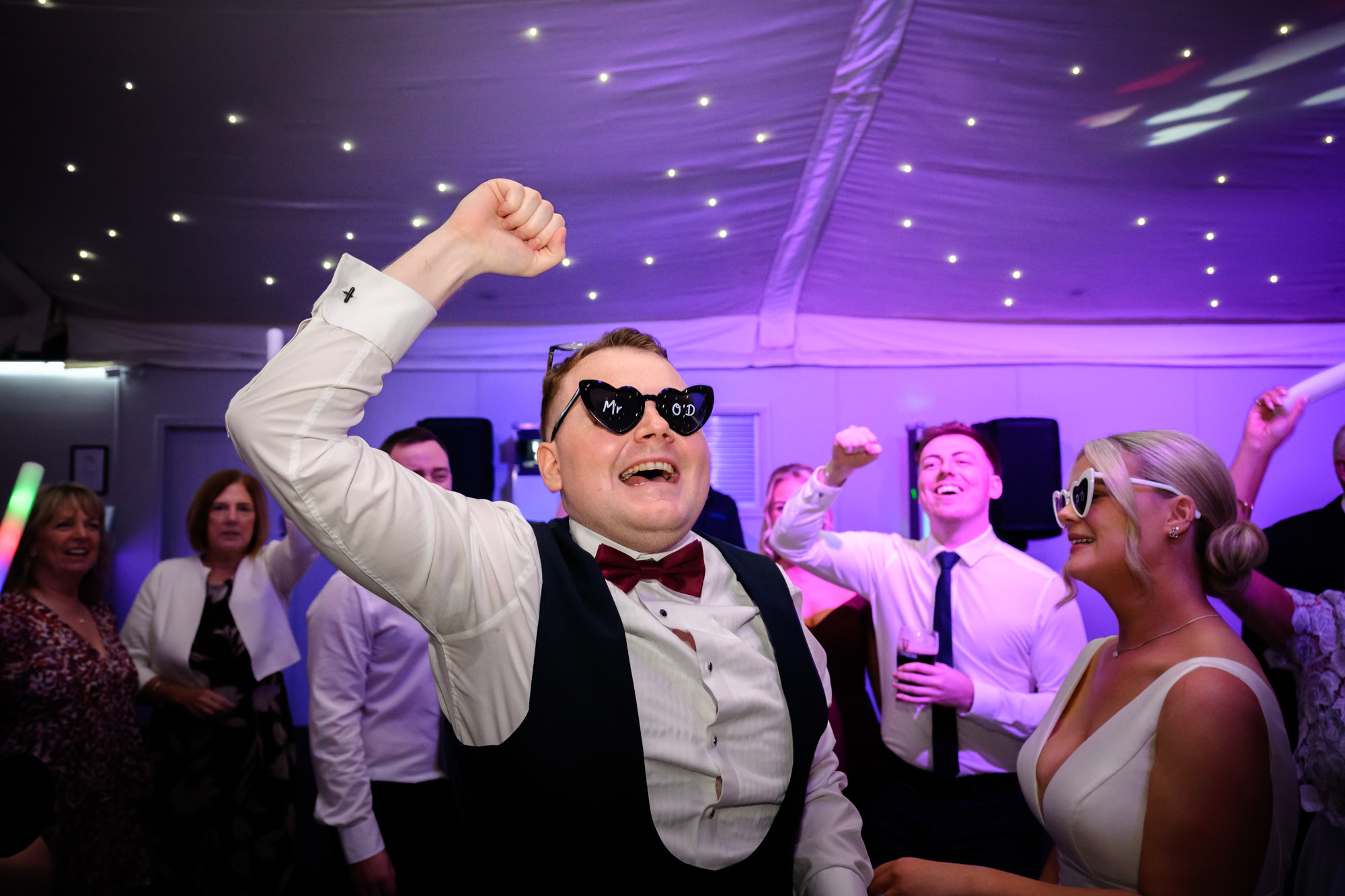 The groom punching the air with joy on the dance floor at Nunsmere Hall.