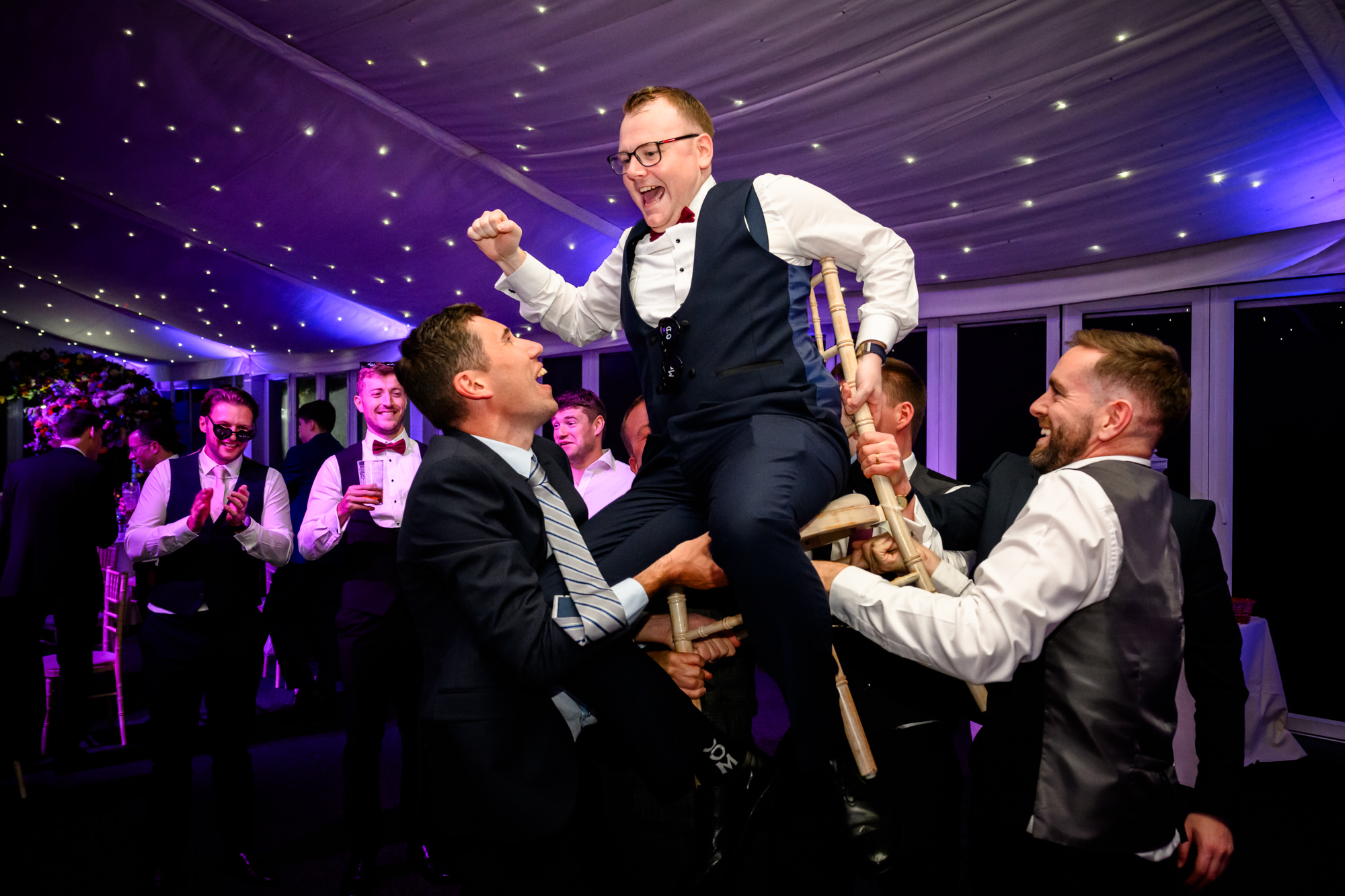 The groom being lifted into the air by his groomsmen on the dance floor at a wedding at Nunsmere Hall.