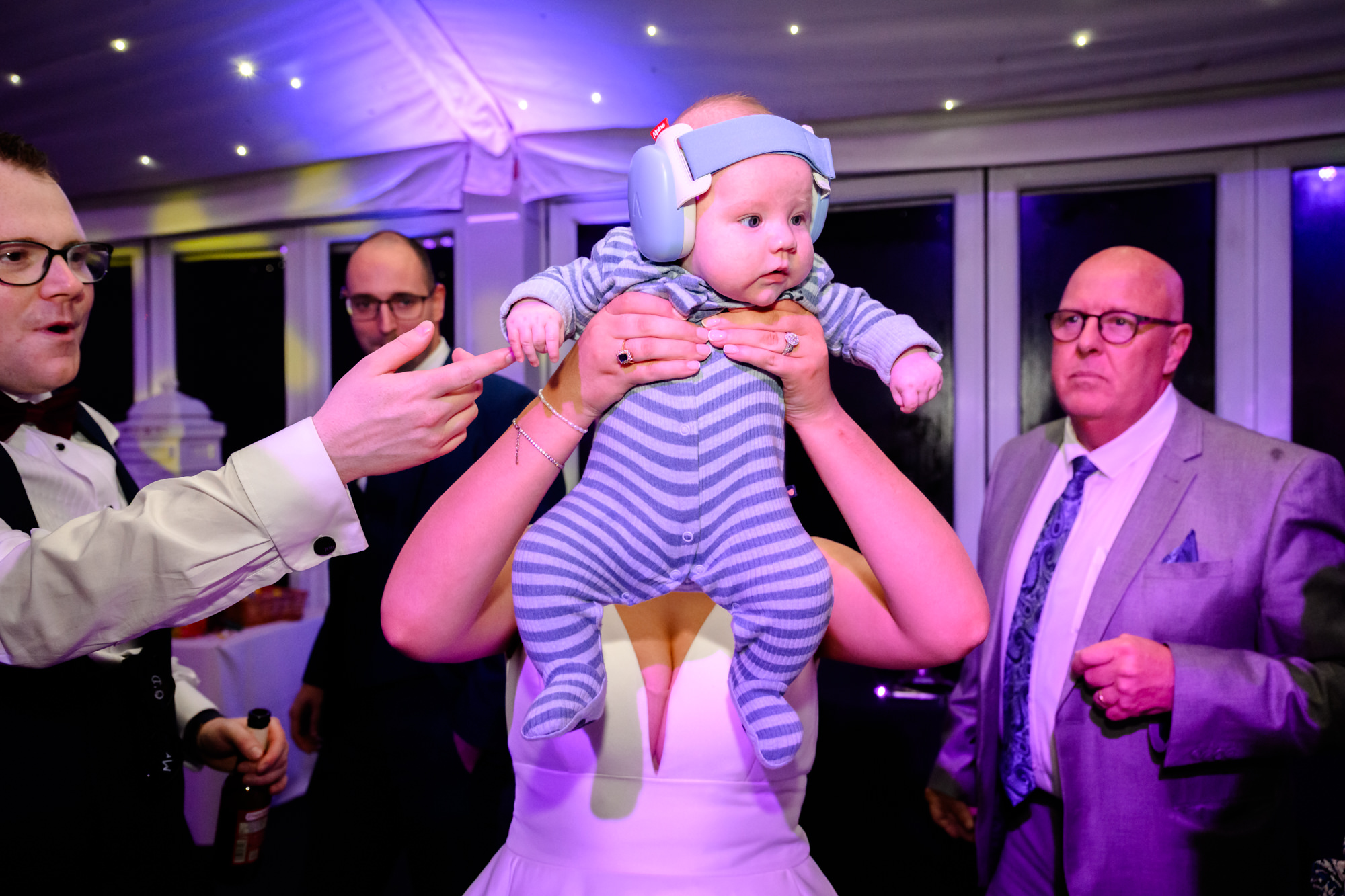 A baby being held up in the air Lion King style on the dance floor at Nunsmere Hall.