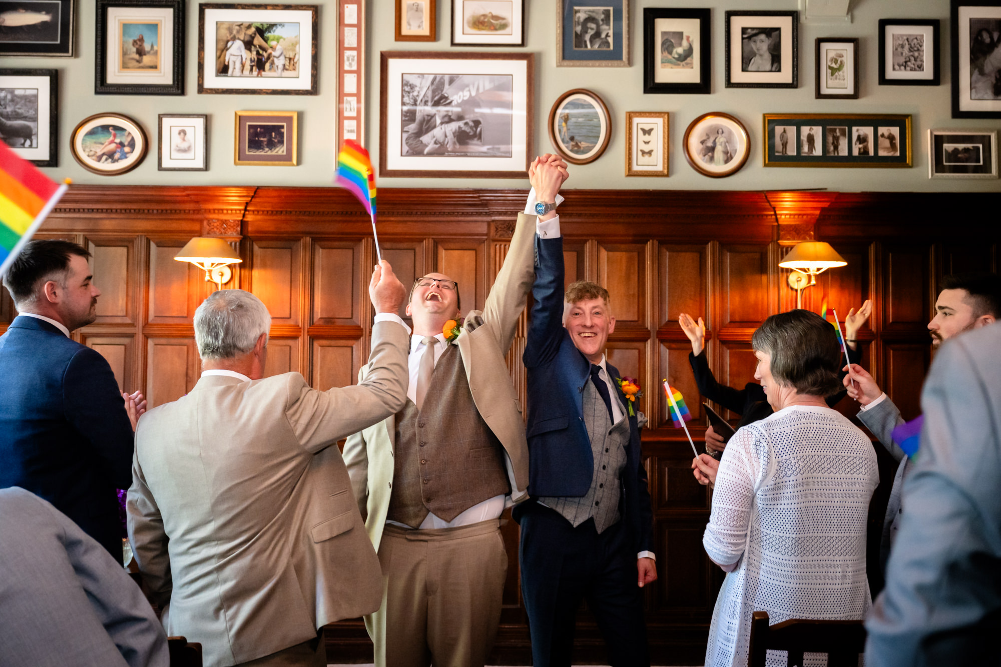 Guests wave Pride flags instead of confetti as Marc and Dom celebrate at The Oakfield.