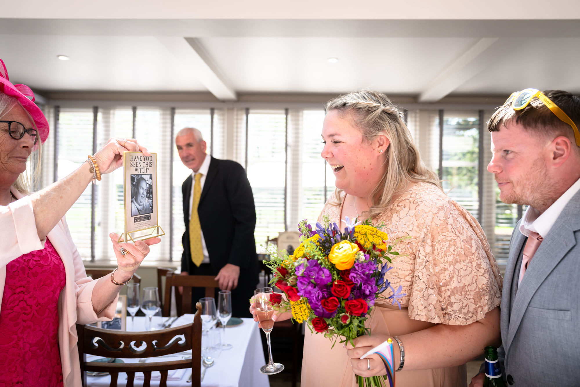 Guests laugh over one of the couple's "Wanted Witch" posters at the drinks reception.