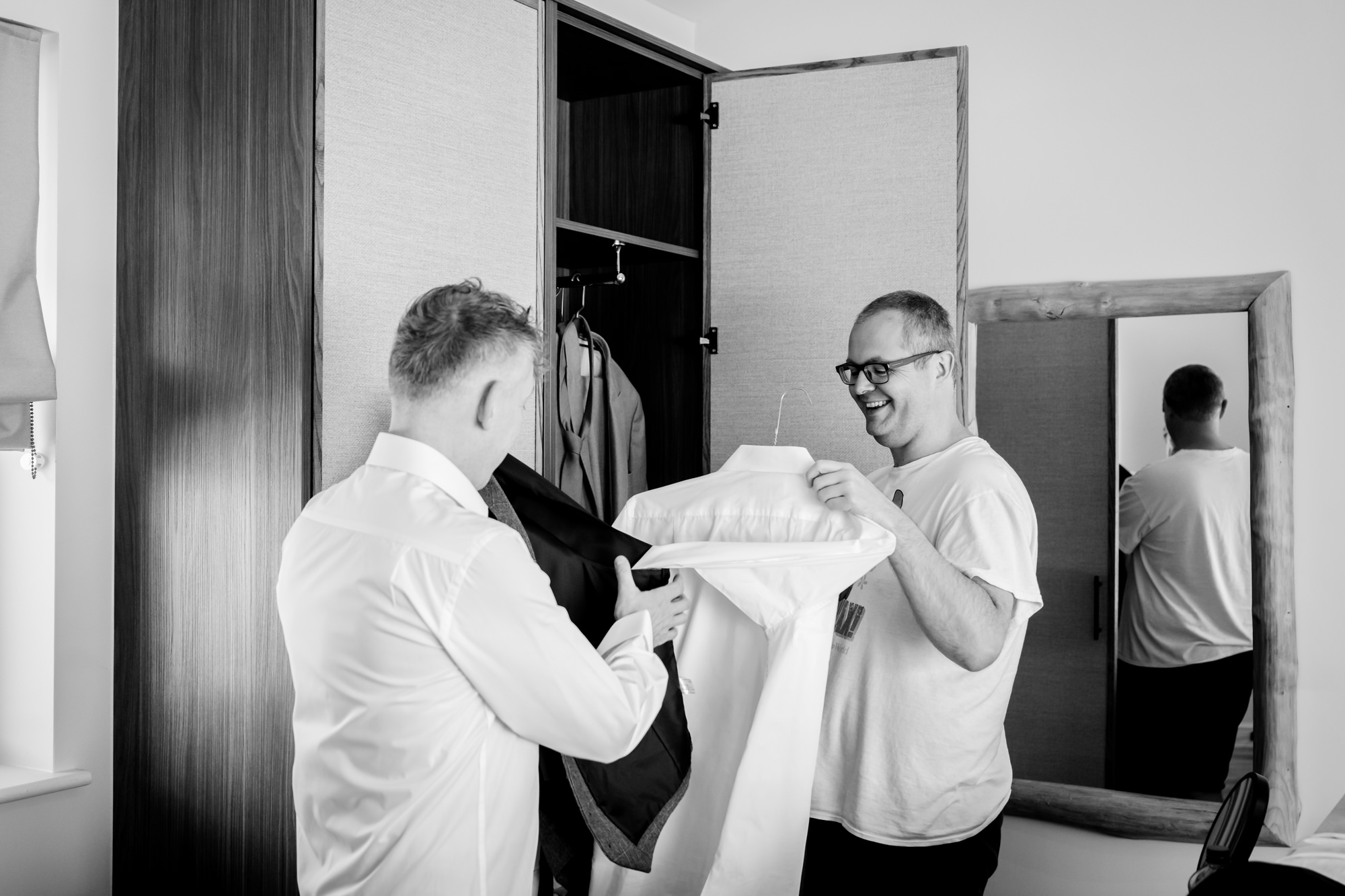 One of the grooms is handed his shirt by a friend during morning prep at The Reserve.