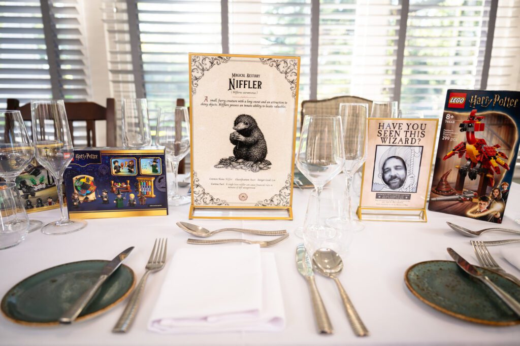 The Niffler table name card on a set table, with Harry Potter Lego and a Wanted poster.