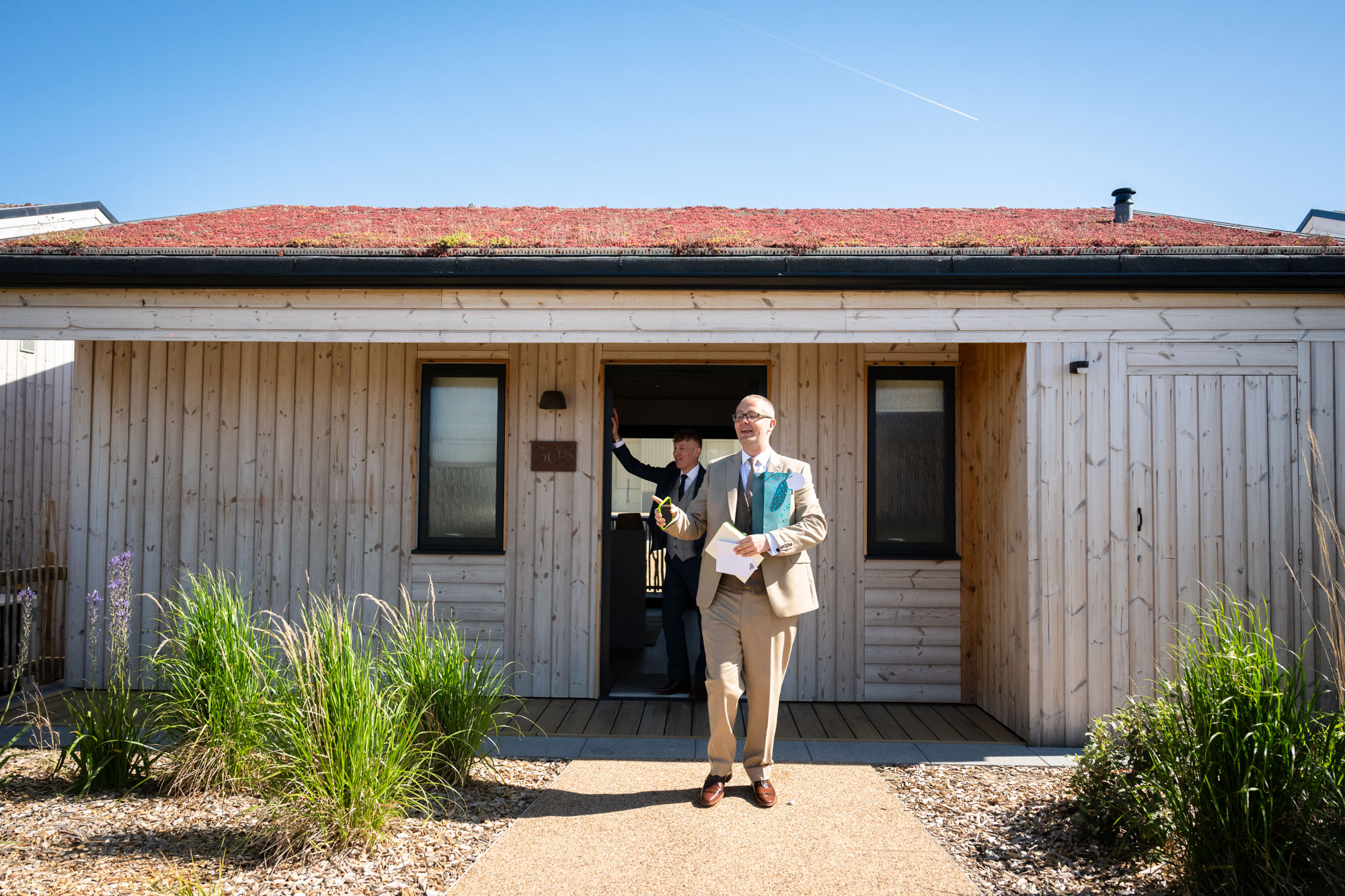 Dom steps out of the lodge at The Reserve, Chester Zoo's on-site accommodation, with Marc in the doorway behind.