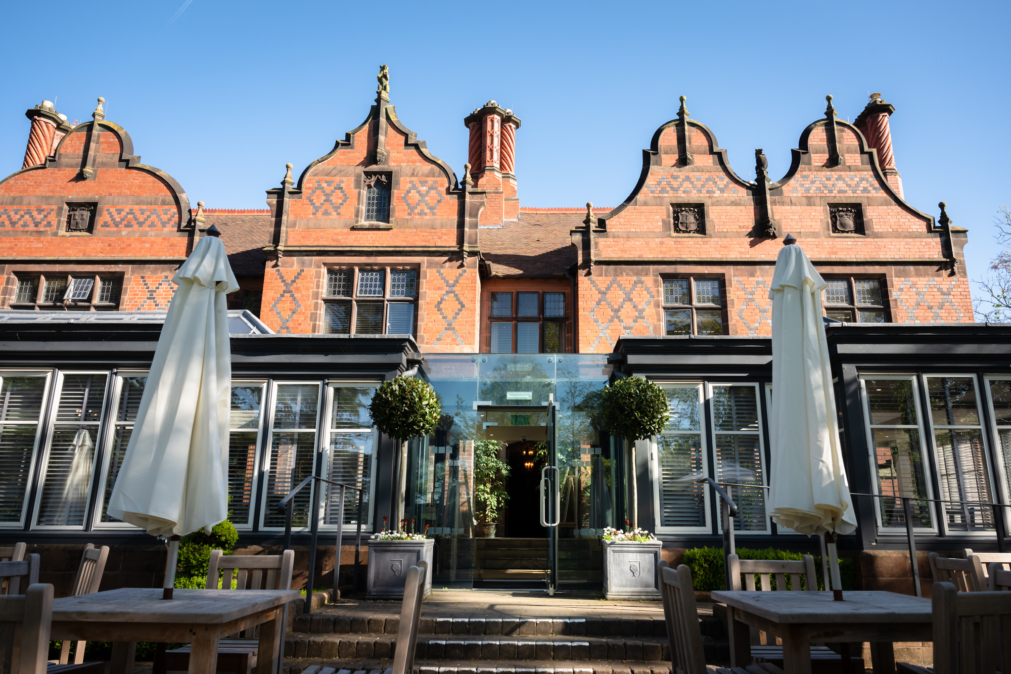 Front of The Oakfield at Chester Zoo showing the Orangery entrance, with patio furniture, topiary plants and floor-to-ceiling windows