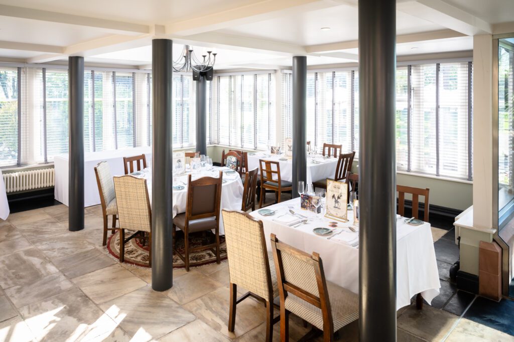 The Orangery at The Oakfield Chester Zoo set for a wedding breakfast, with white linen tables, glassware and large windows on three sides