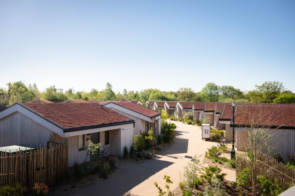Aerial view of the lodge village at The Reserve Chester Zoo, with pale timber lodges, terracotta roofs and planted garden borders