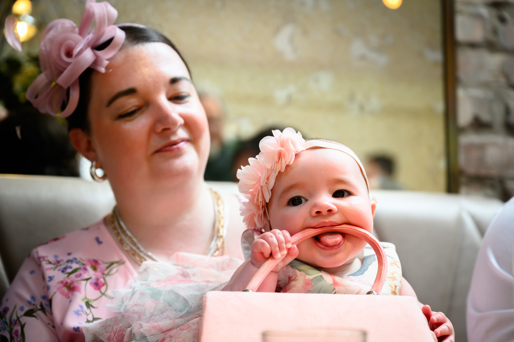 A wedding guest holding a baby during the drinks reception at The Castlefield Rooms, the baby chewing on her mother's handbag strap.