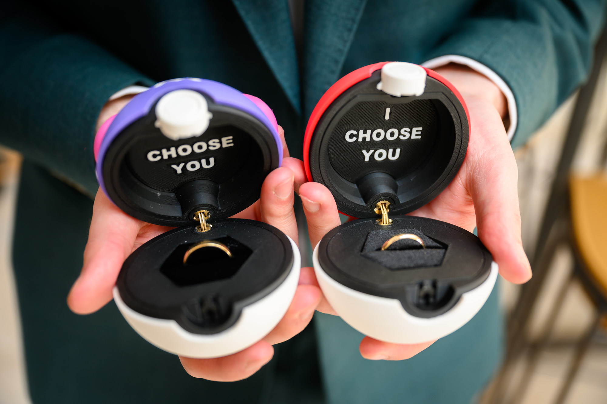 Two custom pokeball ring boxes open to reveal the wedding rings, each inscribed with I Choose You, held by the groom at The Castlefield Rooms wedding.
