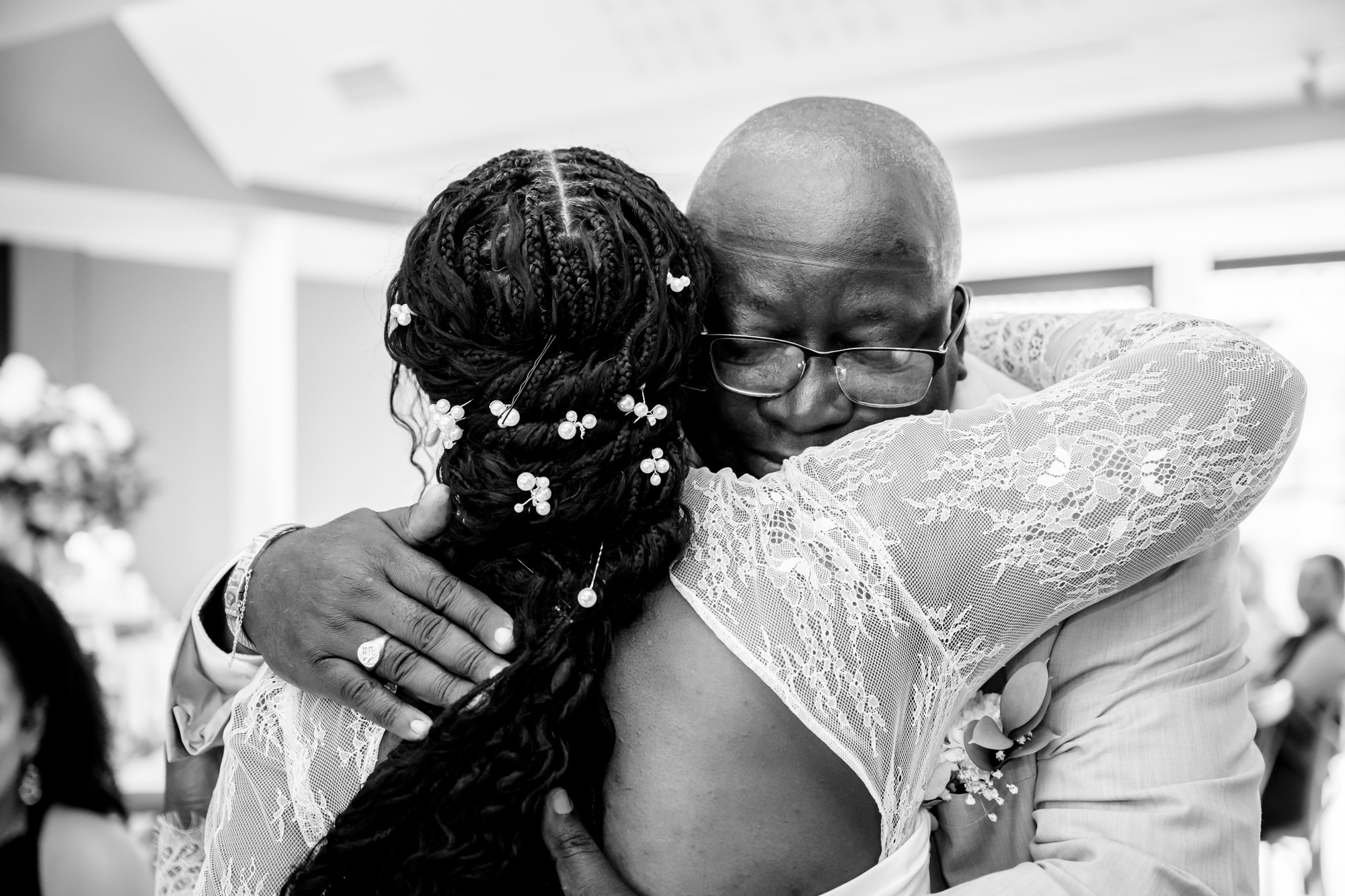 Black and white close-up of the bride hugging her father after speeches in the Merchant Room at The Castlefield Rooms.