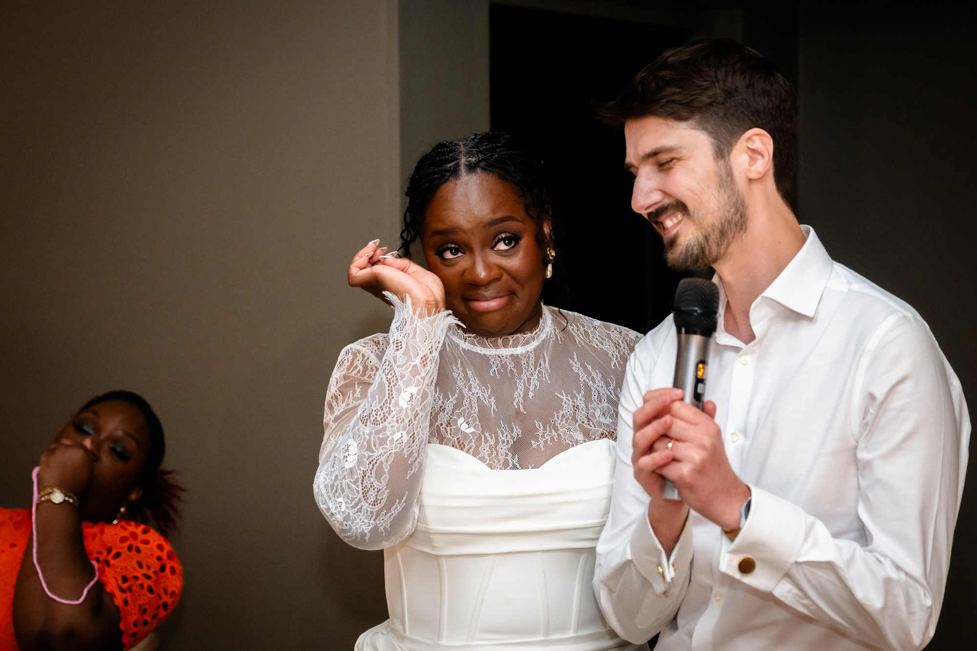 The bride wiping a tear while the groom delivers their joint speech in the Merchant Room at The Castlefield Rooms during the wedding reception.